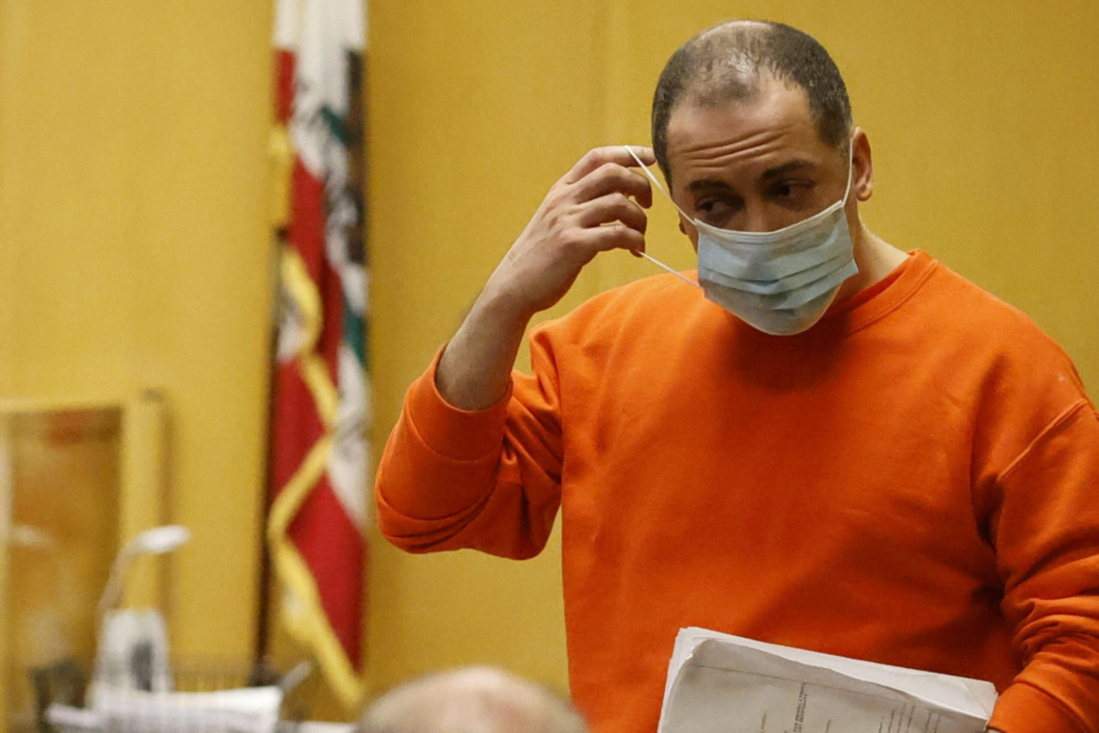 A man wears a mask in a courtroom.