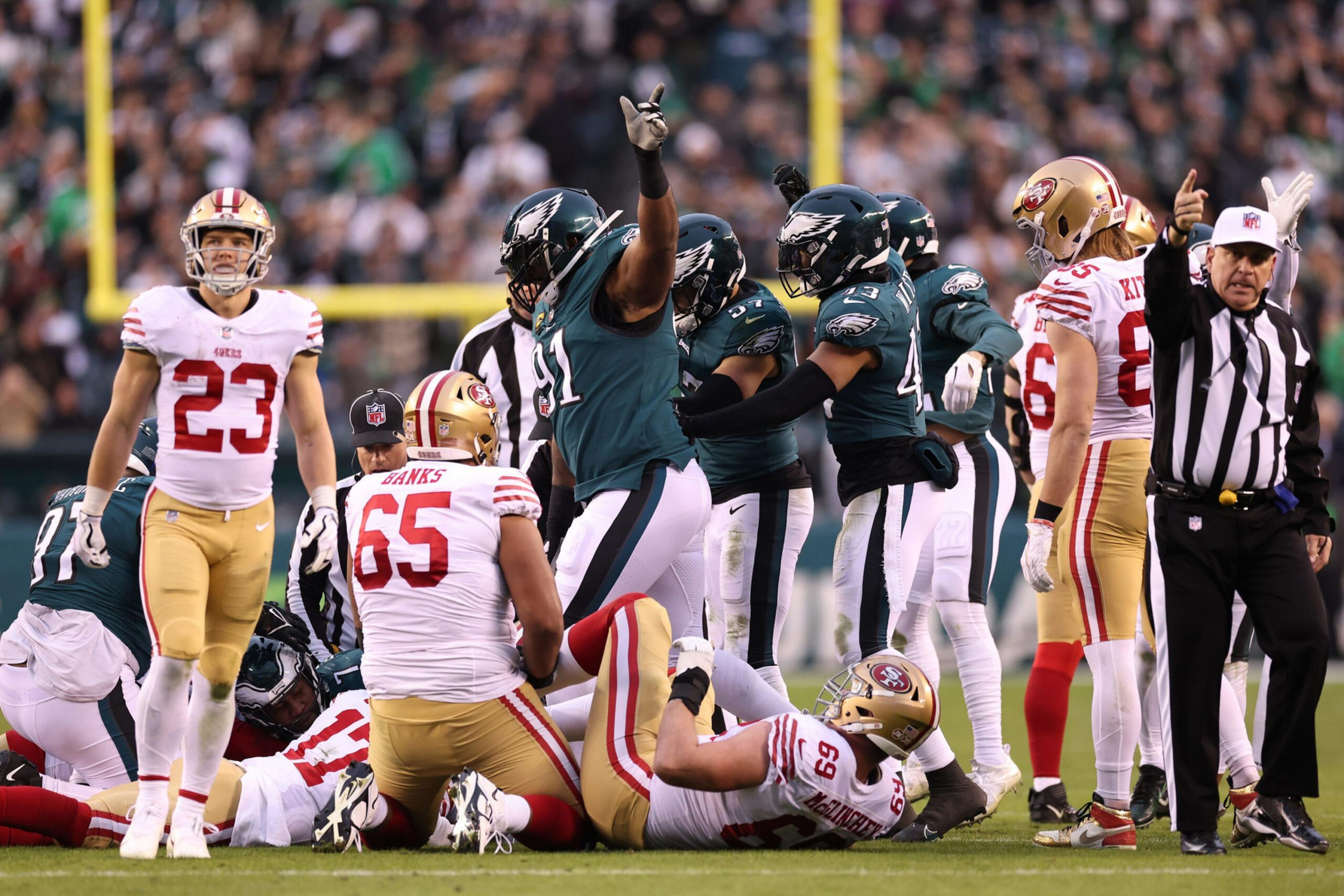 Philadelphia Eagles players celebrate on the field as San Francisco 49ers players are down, with a referee signaling and players reacting around them.