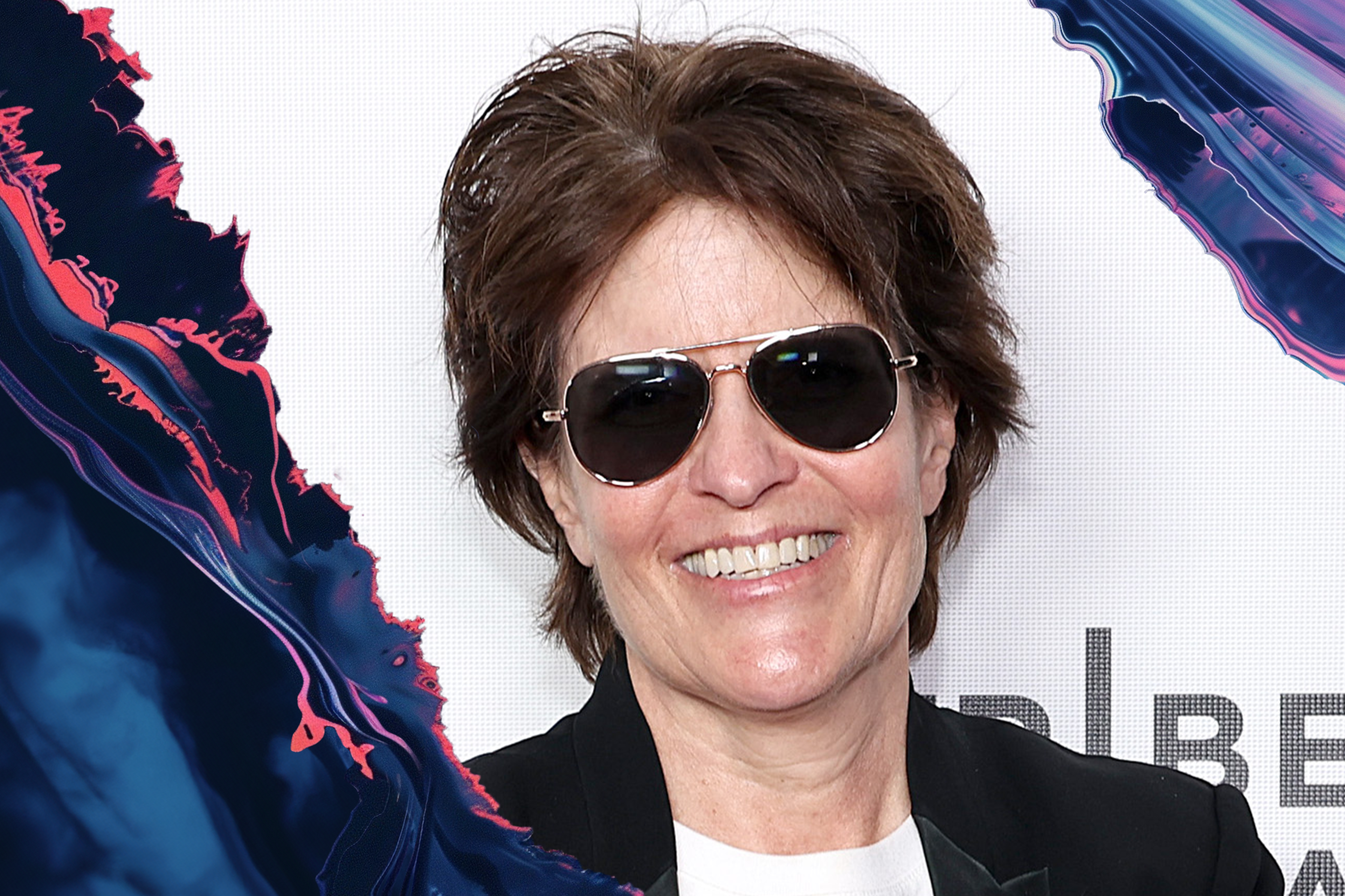 A photo of a woman with short brown hair with aviator sunglasses on.