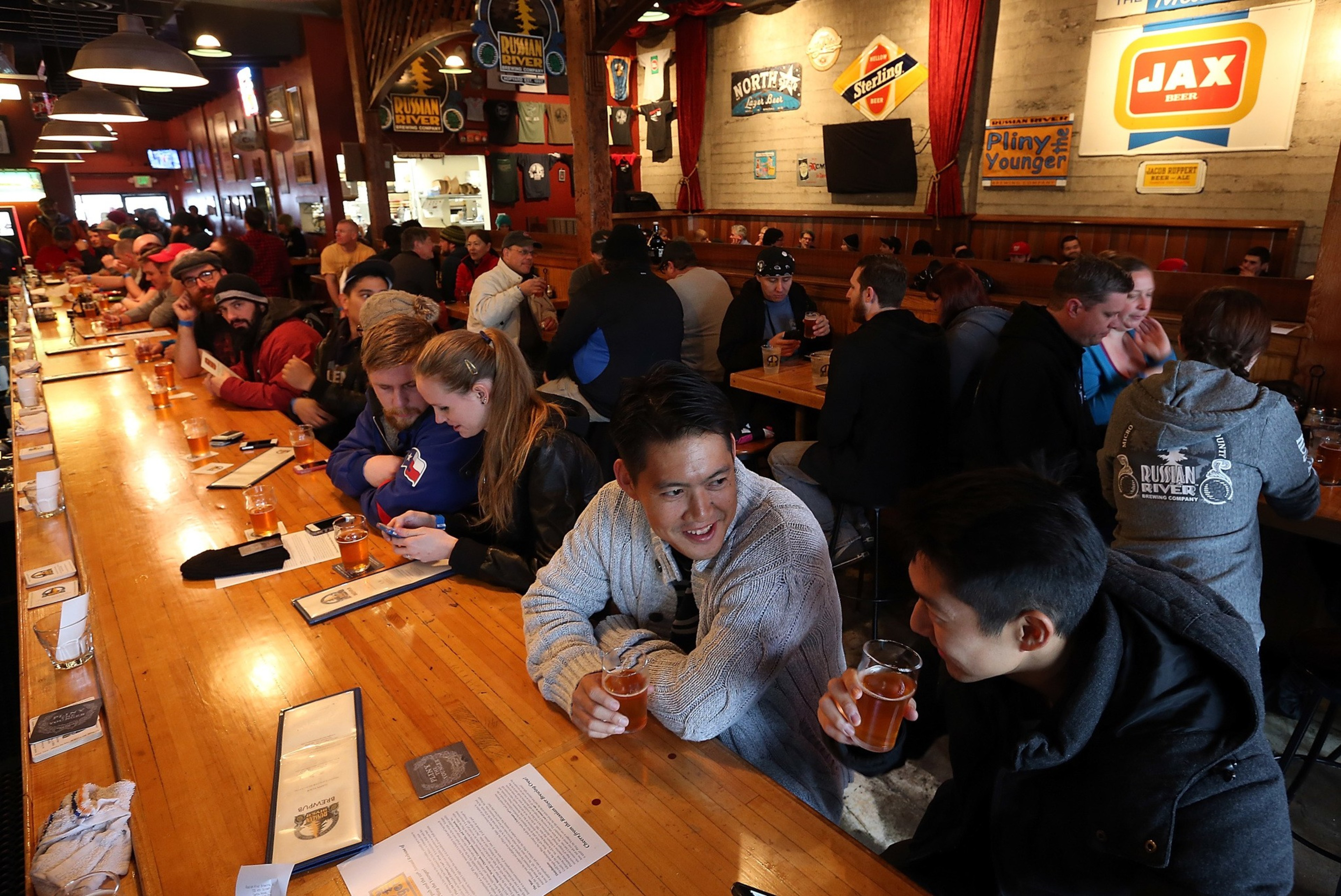 People sit at a long table drinking beer in a pub.