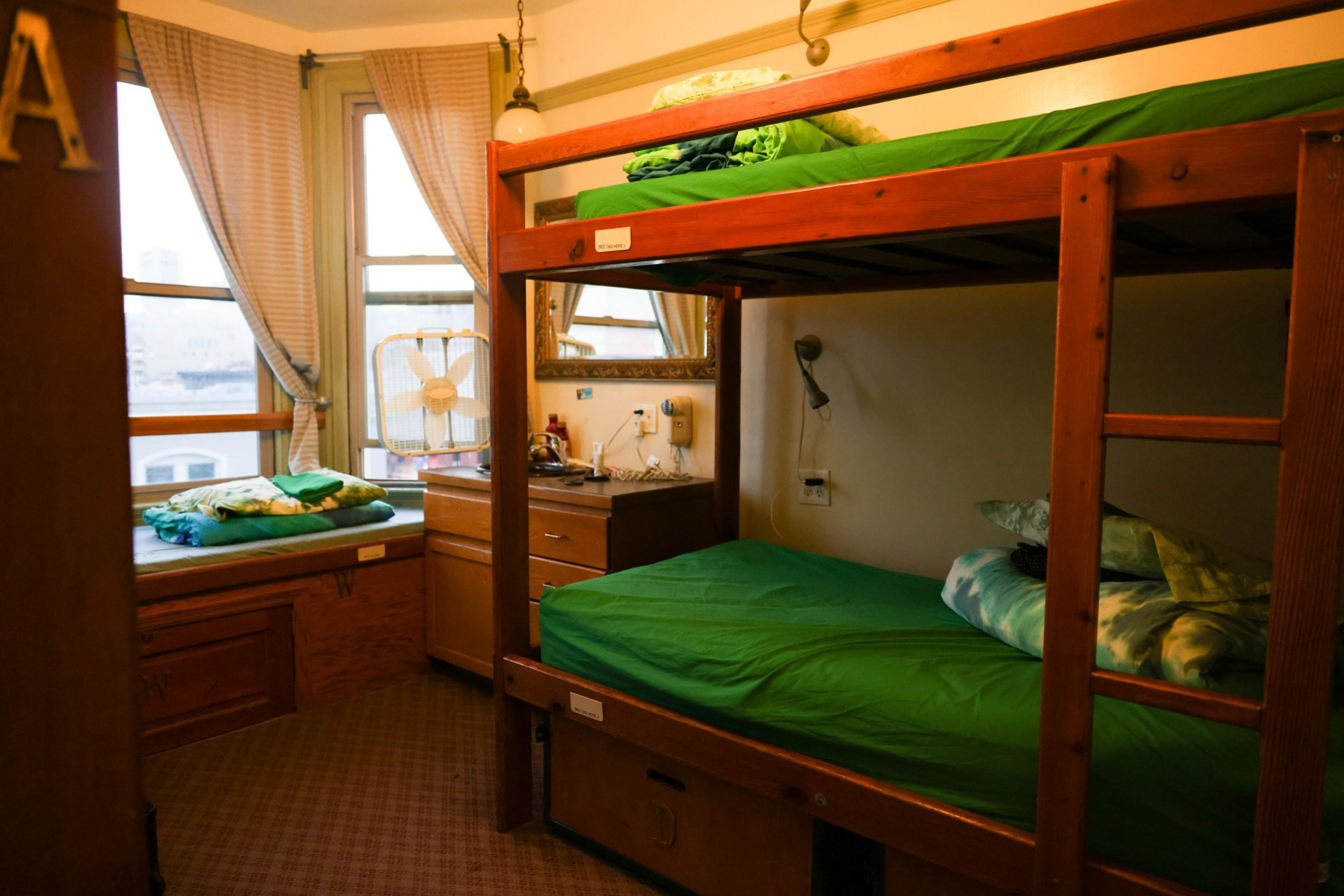 Bunkbeds with green shits look out to a gloomy day in San Francisco. 