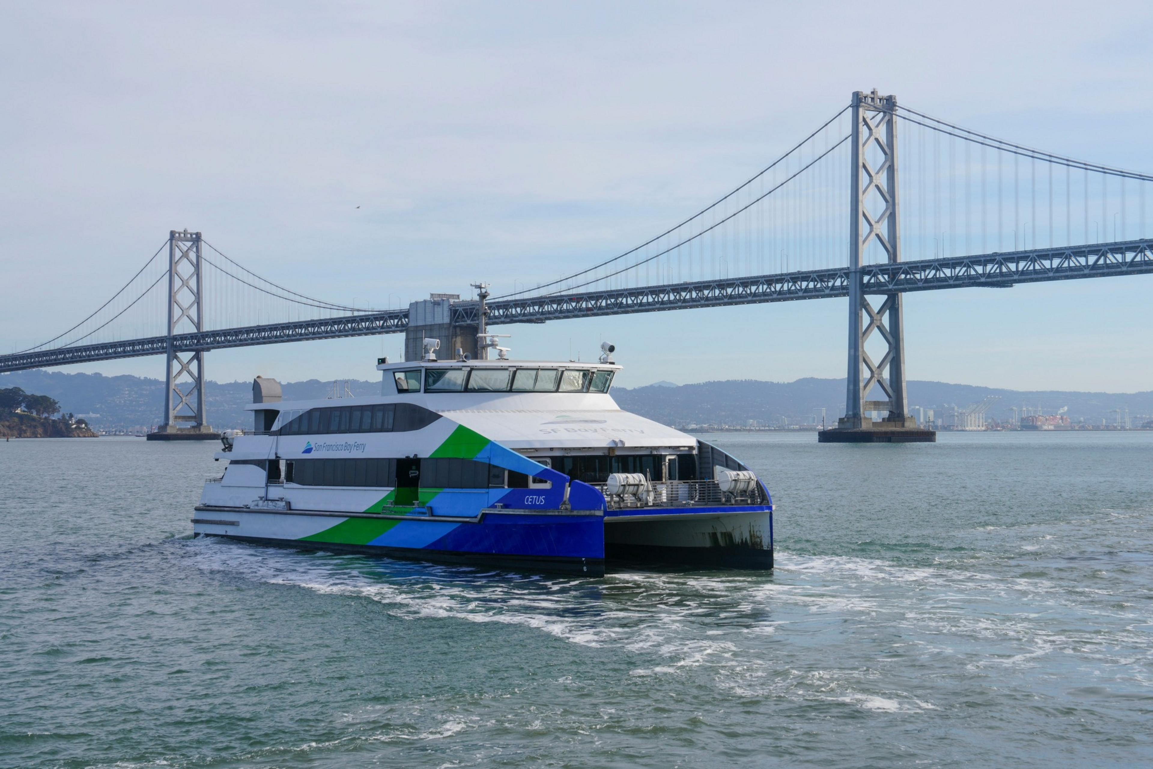 A modern ferry with blue, green, and white colors moves through the ...