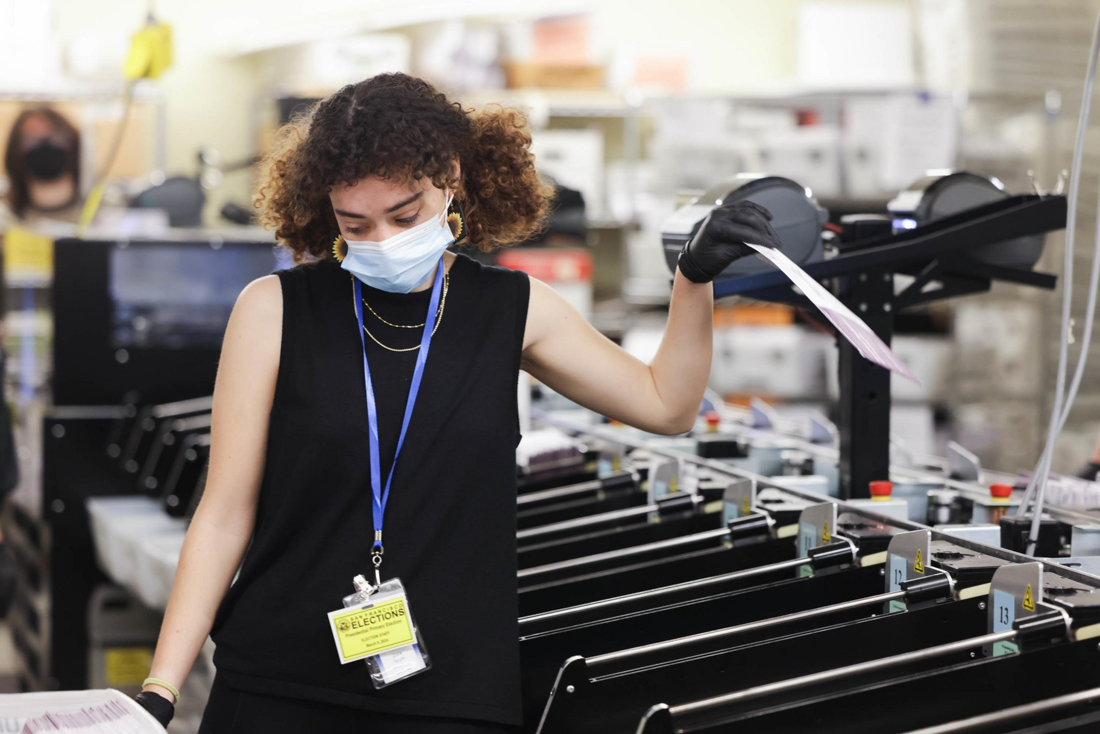 A worker in a mask sorts ballots