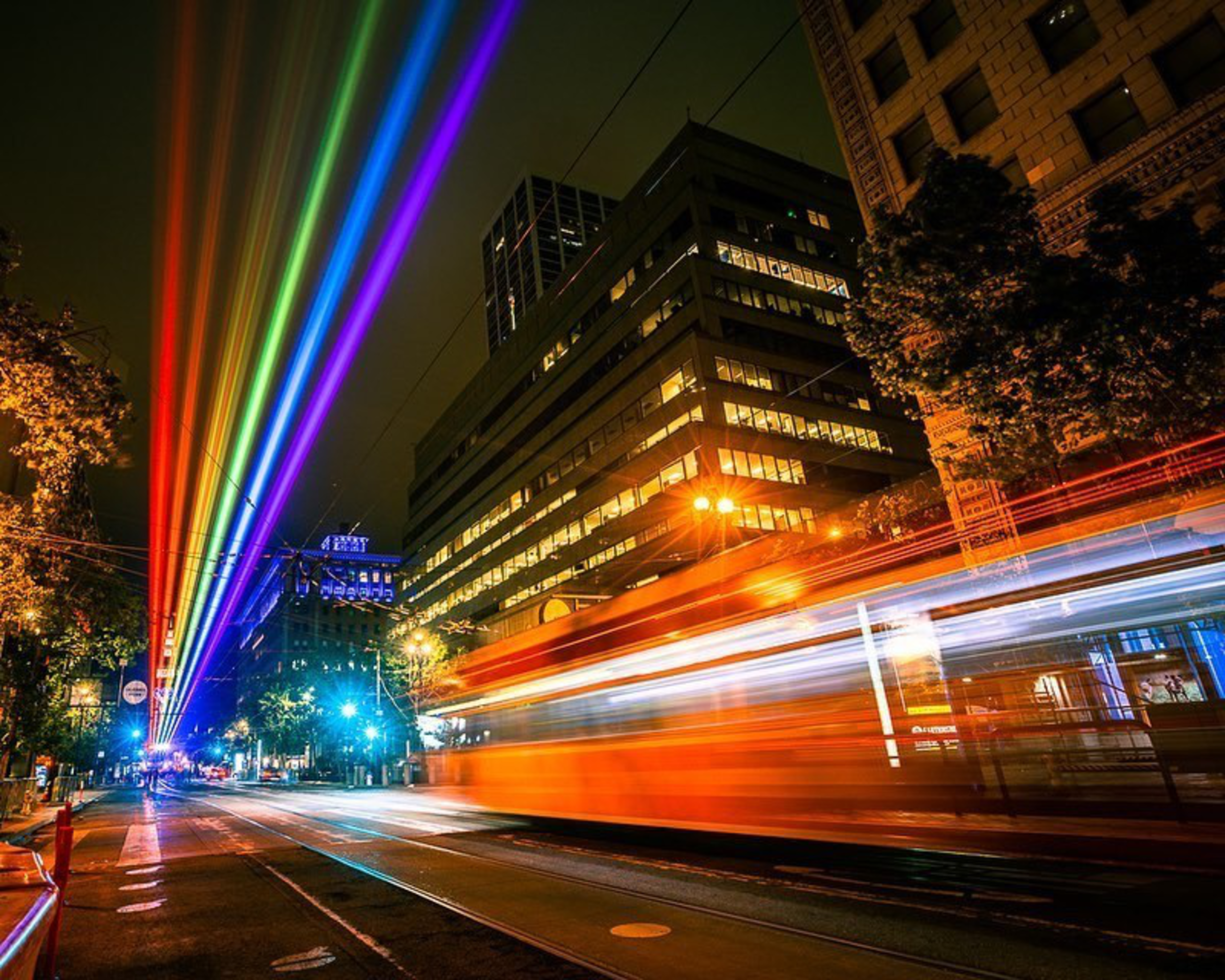 An artfully blurry image of rainbow laser beams in Downtown San Francisco with an F-Market streetcar.