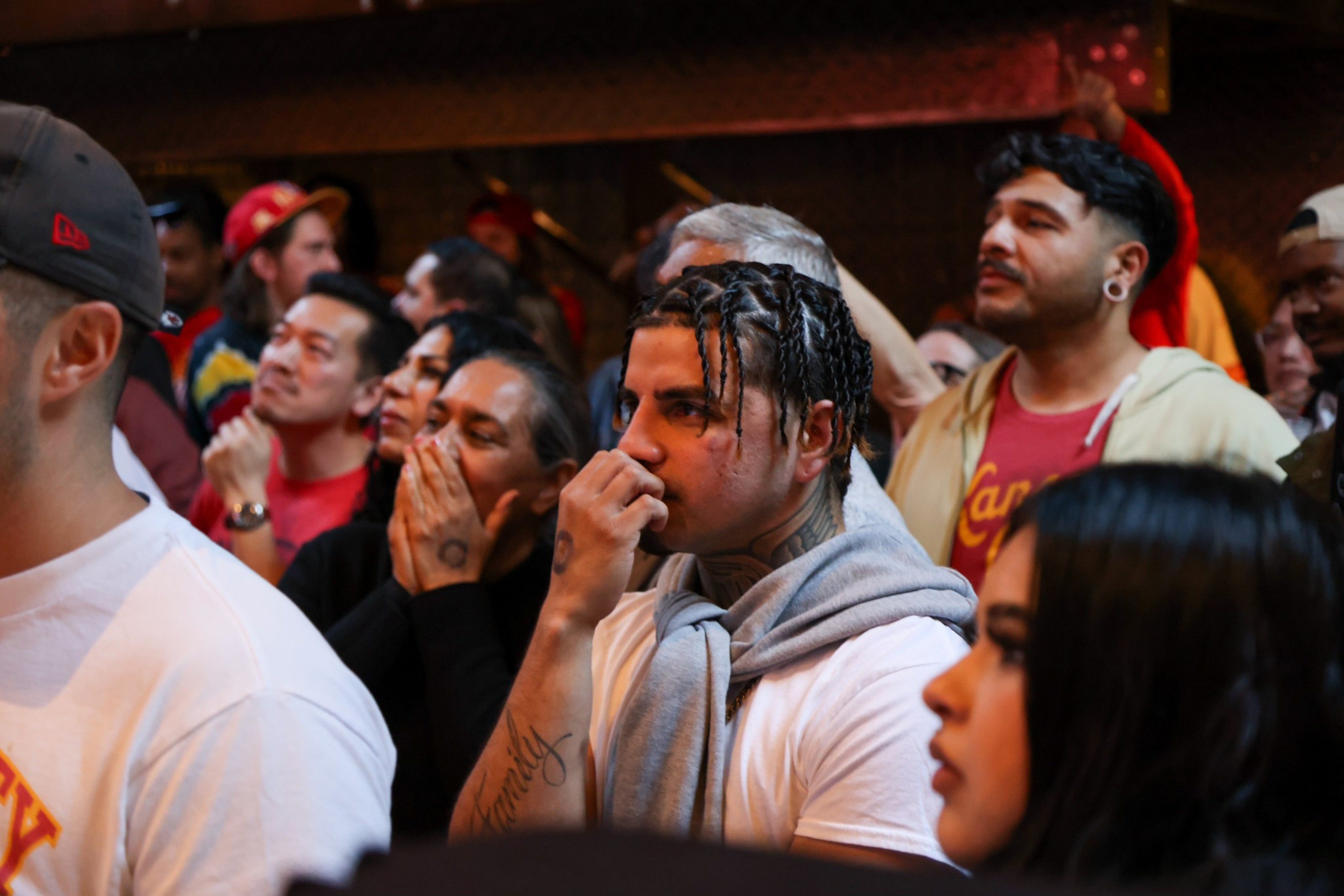 Fans watch football game on TV with hands raised to face