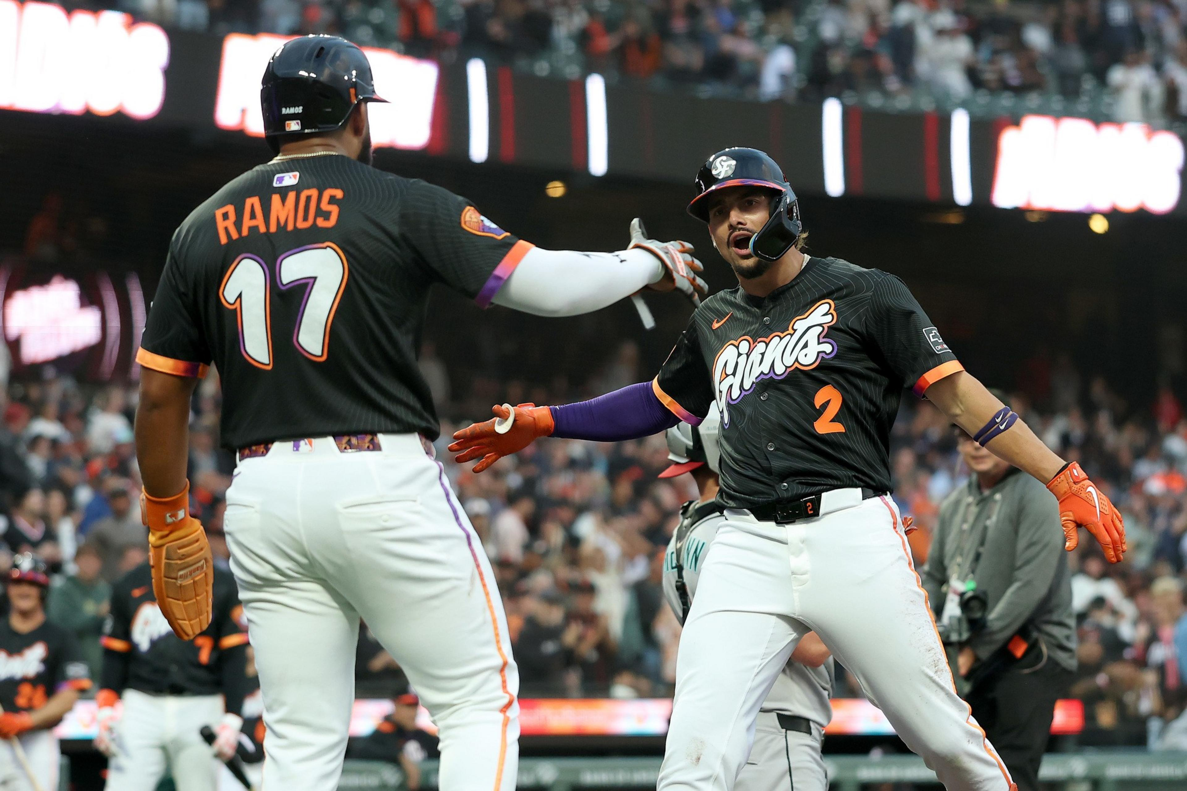 Two San Francisco Giants players, one wearing number 17 and the other number 2, are celebrating during a baseball game.