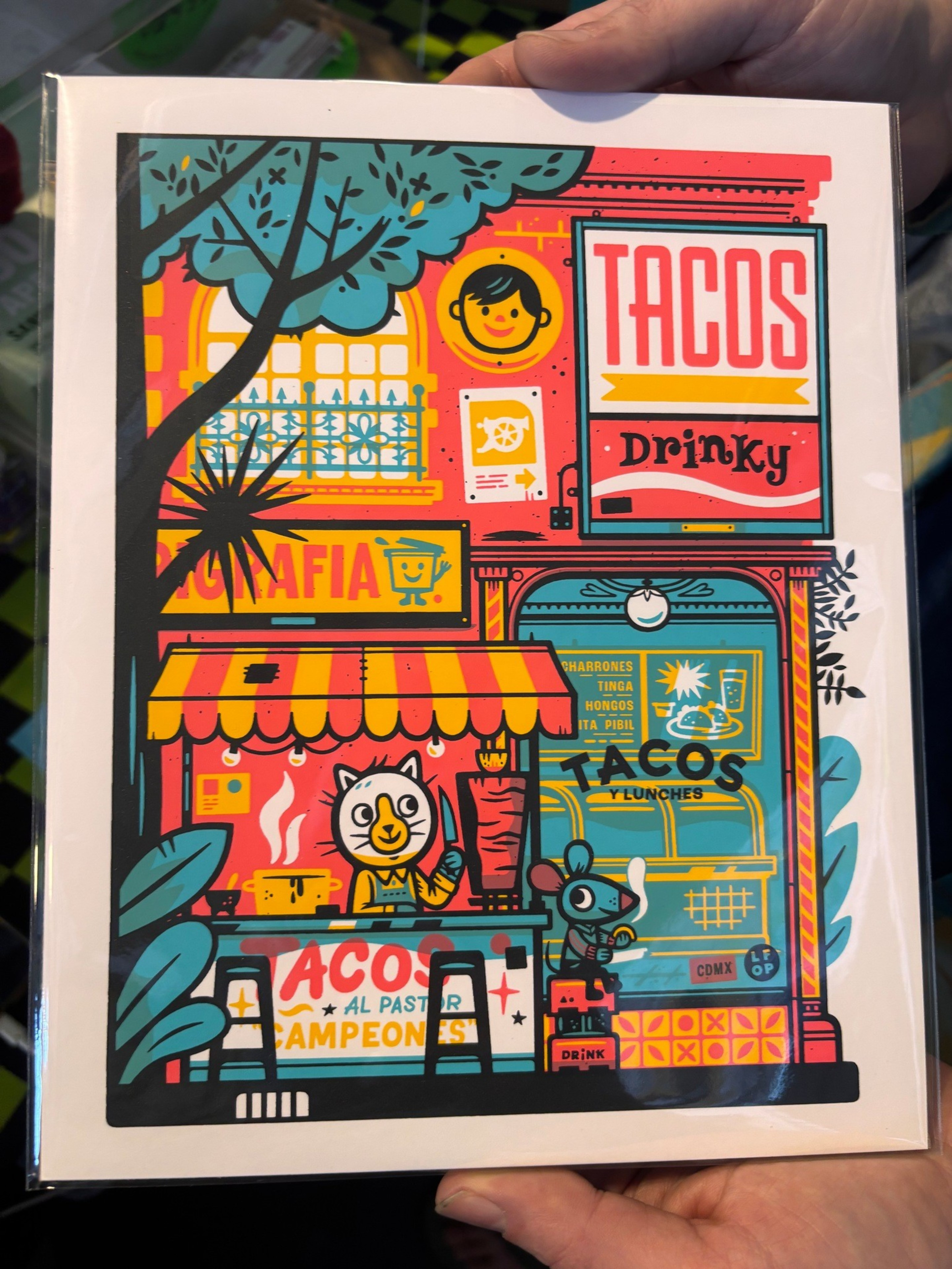 A colorful taco stand with a cat chef holding a taco and a mouse seated nearby under signs reading “Tacos,” “Drinky,” and “Al Pastor Campeones.”