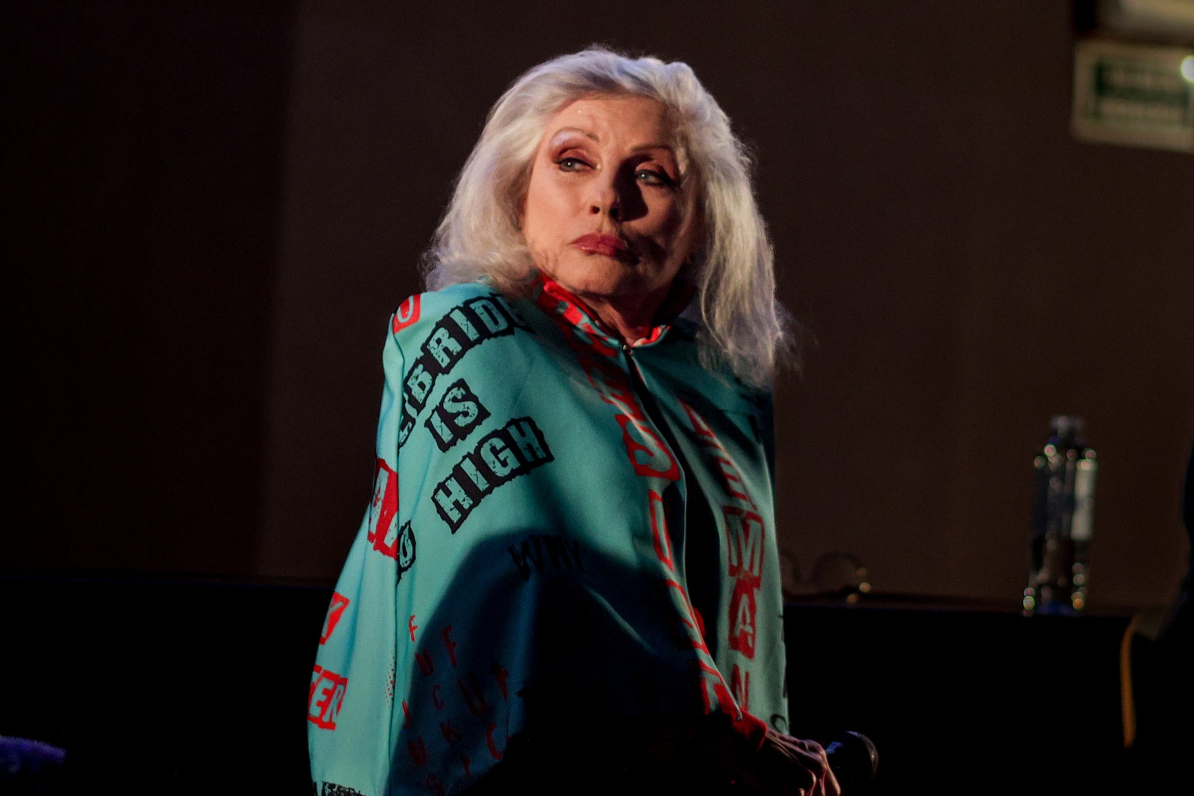 Debbie Harry of Blondie looking over her shoulder in a cloak.
