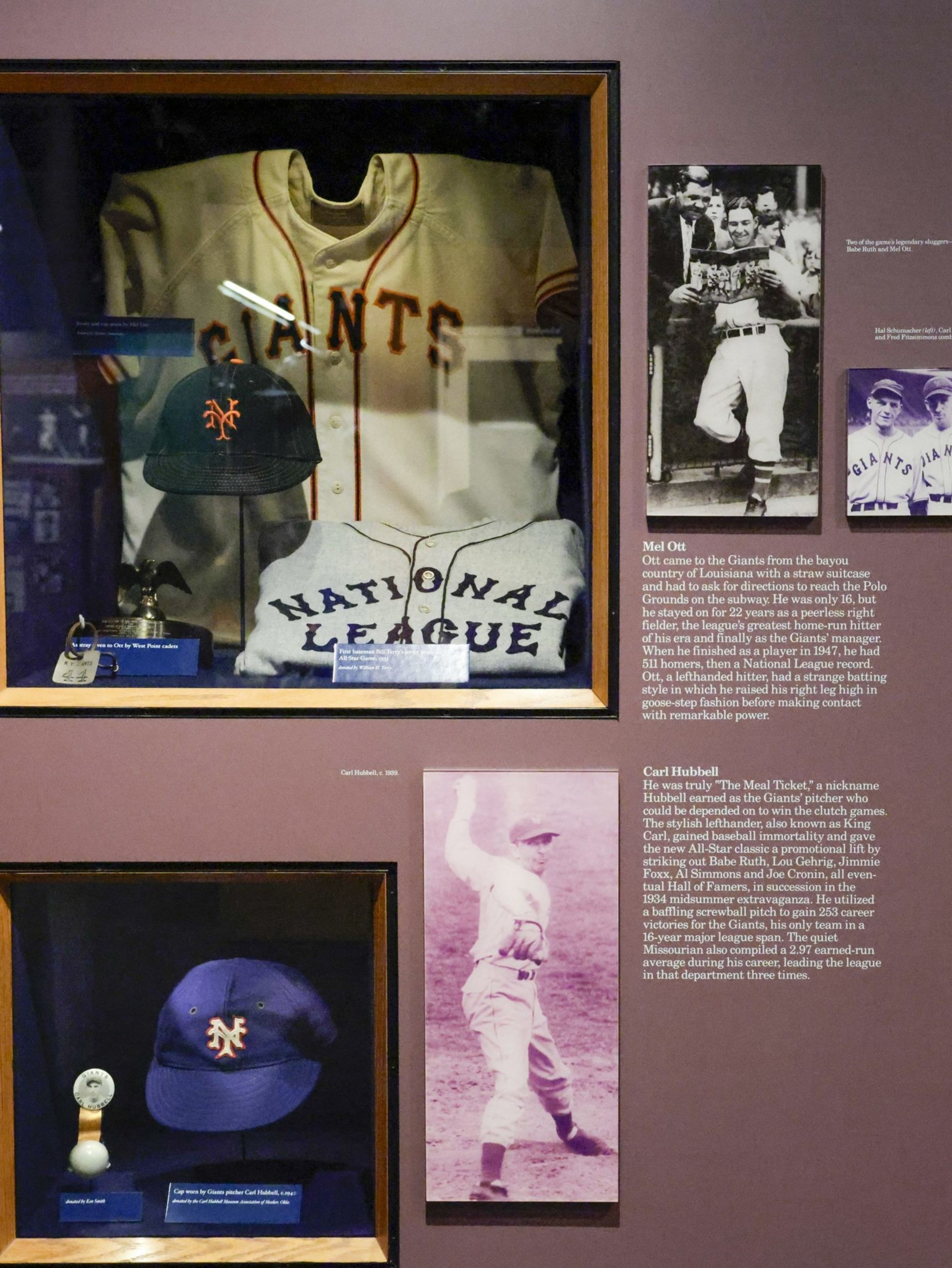 A display case features baseball jerseys, caps, and memorabilia from the Giants, accompanied by vintage photos and descriptions of players Mel Ott and Carl Hubbell.