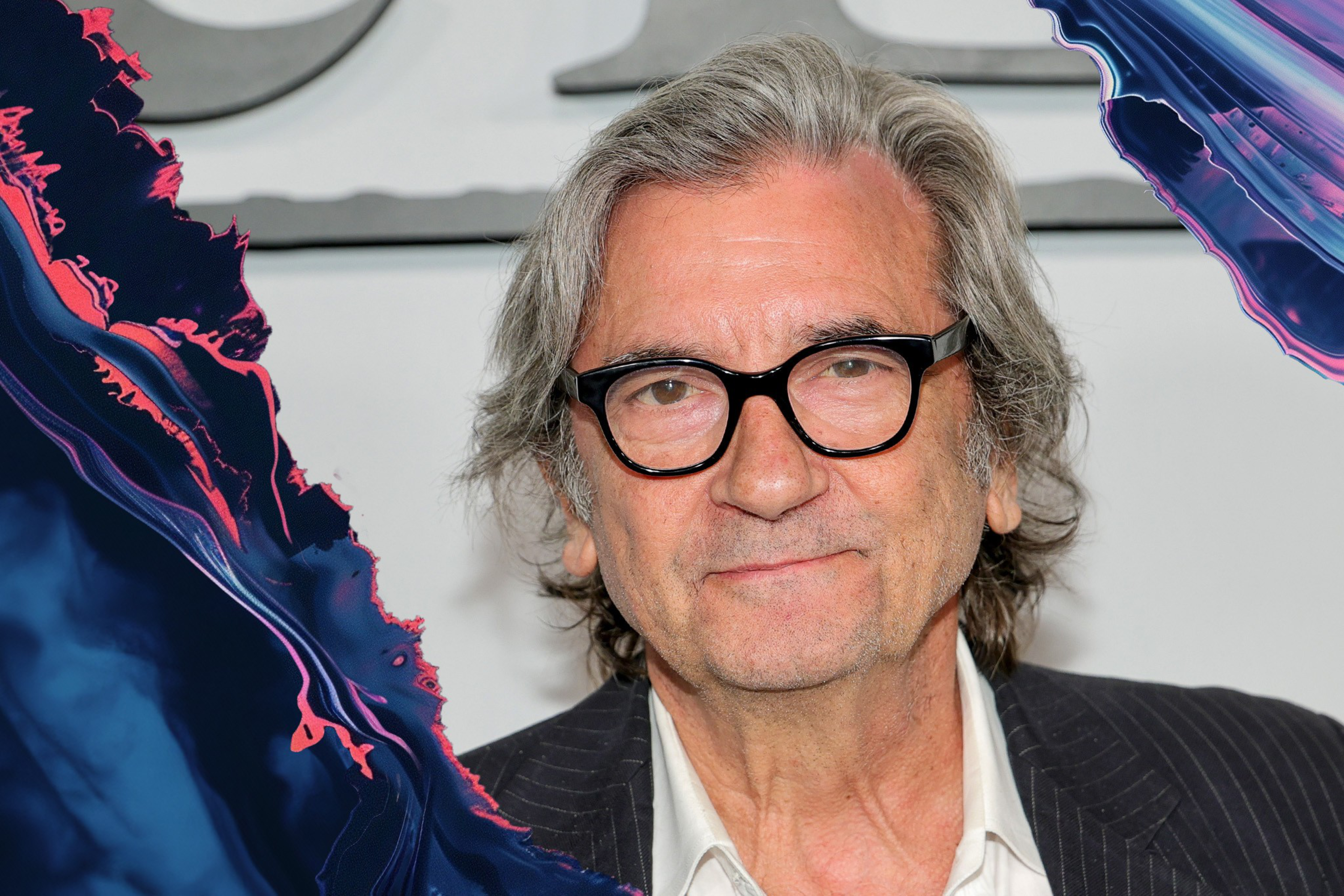 An older person with gray hair and glasses is smiling subtly. They are wearing a white shirt under a pinstripe jacket. The left side has a colorful, abstract effect.