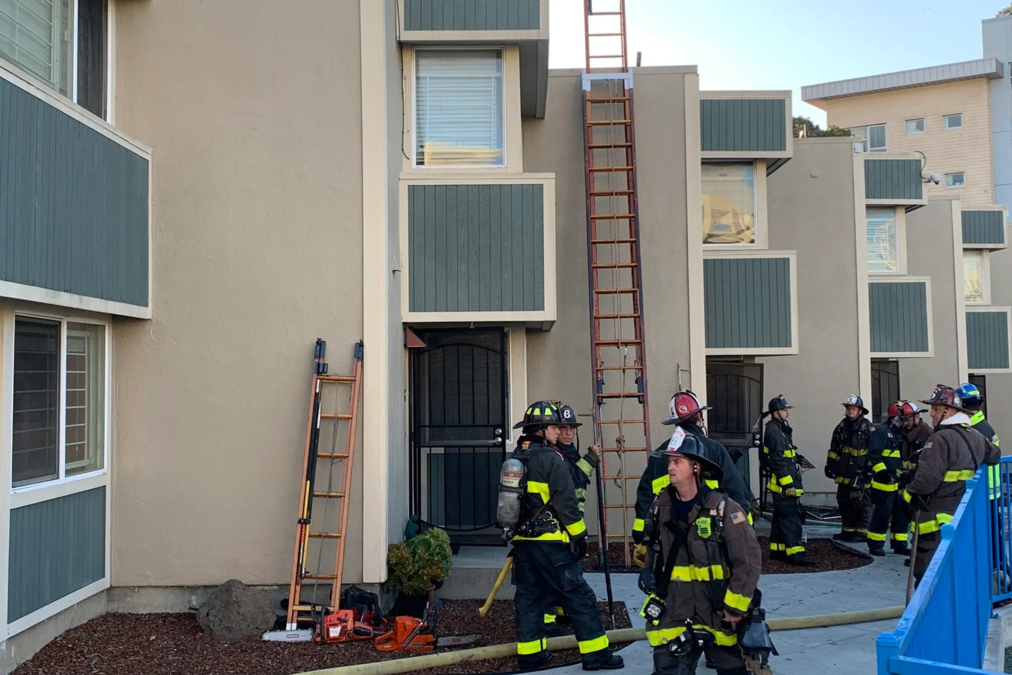 Firefighters stand outside of a home.