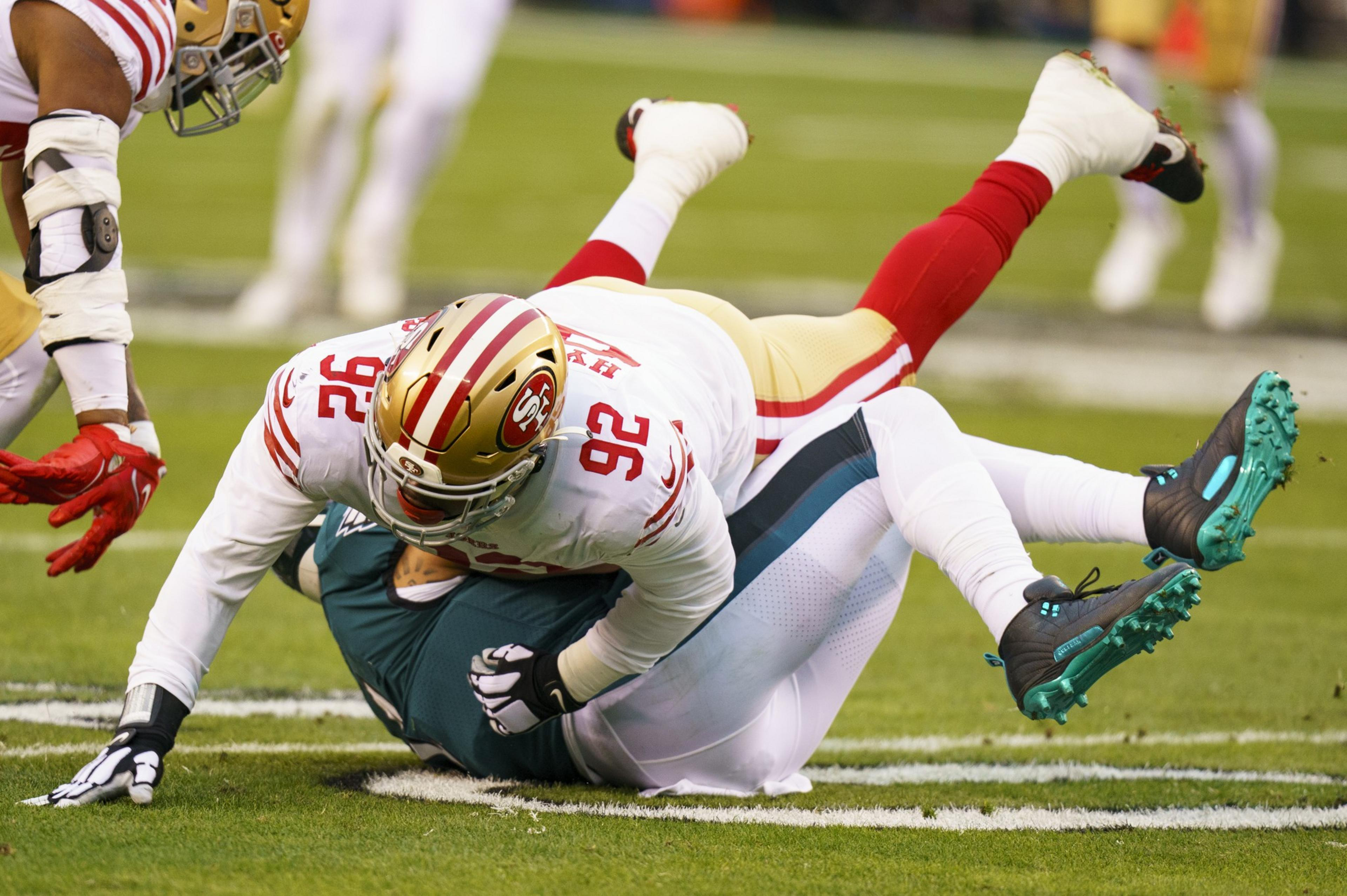 A San Francisco 49ers player tackles a Philadelphia Eagles player on the football field during a game.