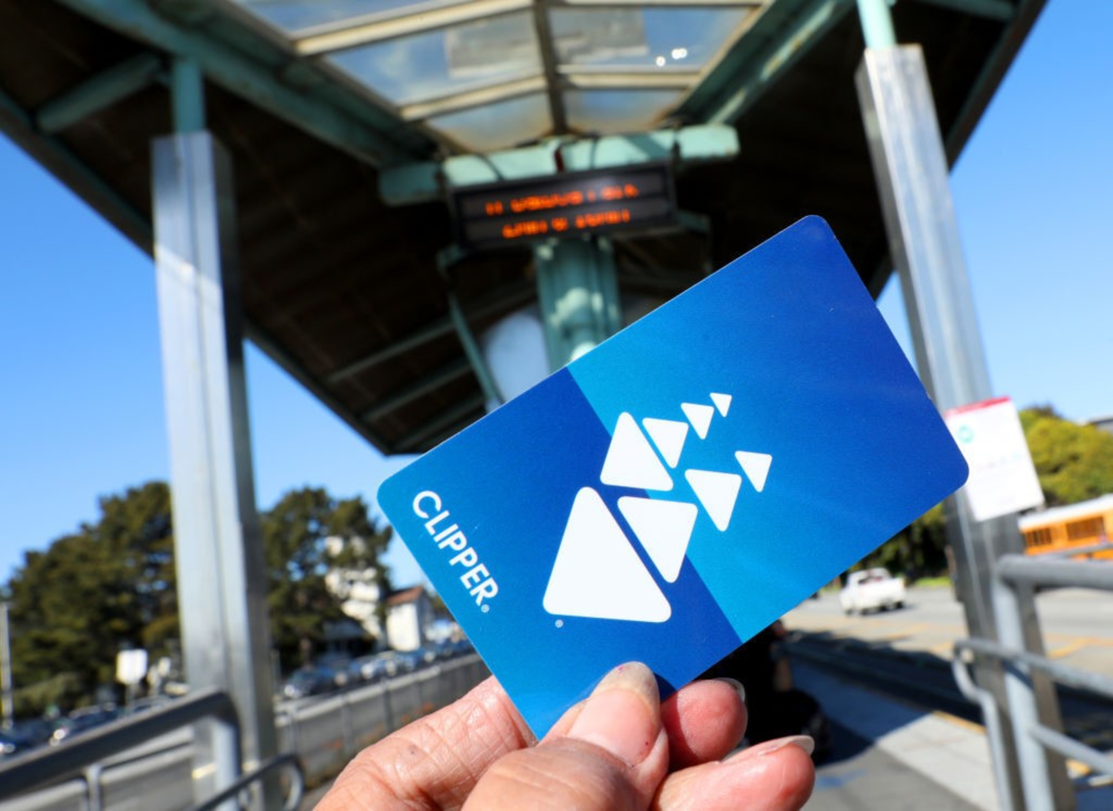 A person's hand holds a bright blue plastic card with white shapes on it in the outline of a clipper ship.