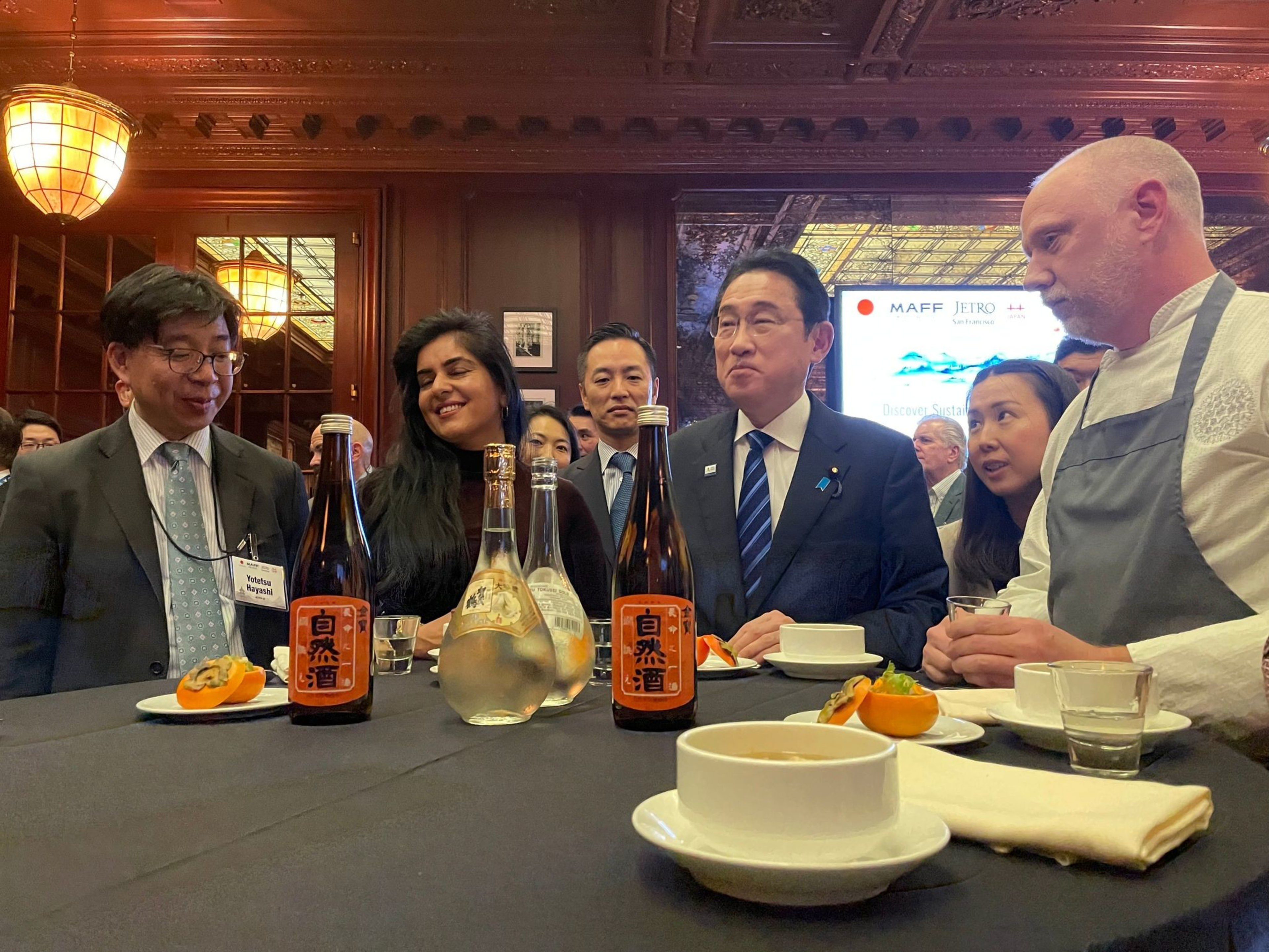 A group of people stand at the table at an dinner event
