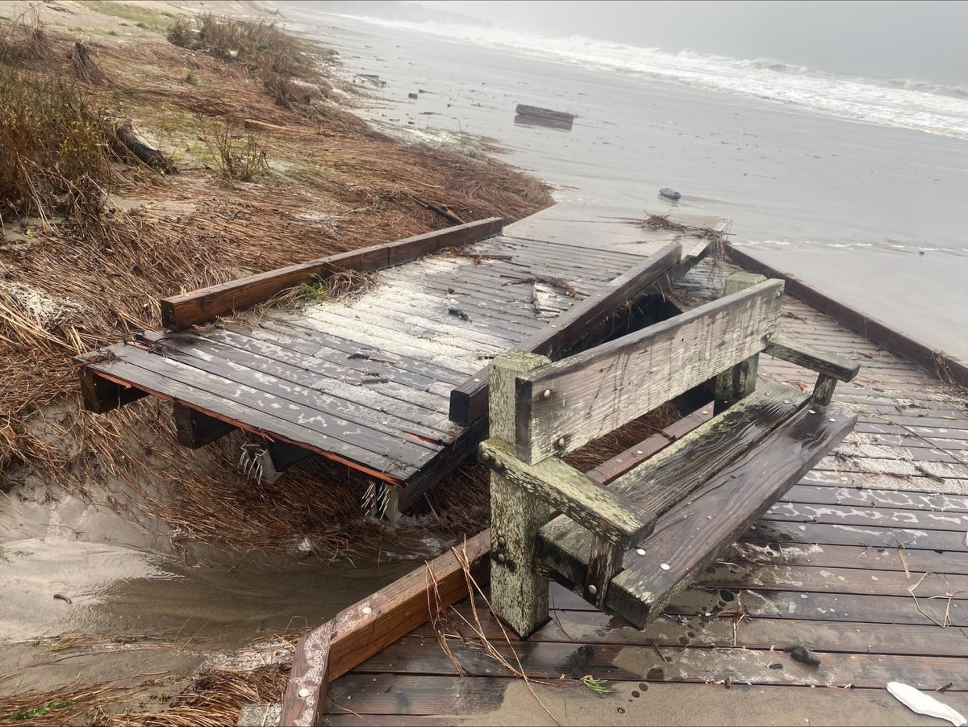 A broken bridge during a storm with the ocean in the background. 
