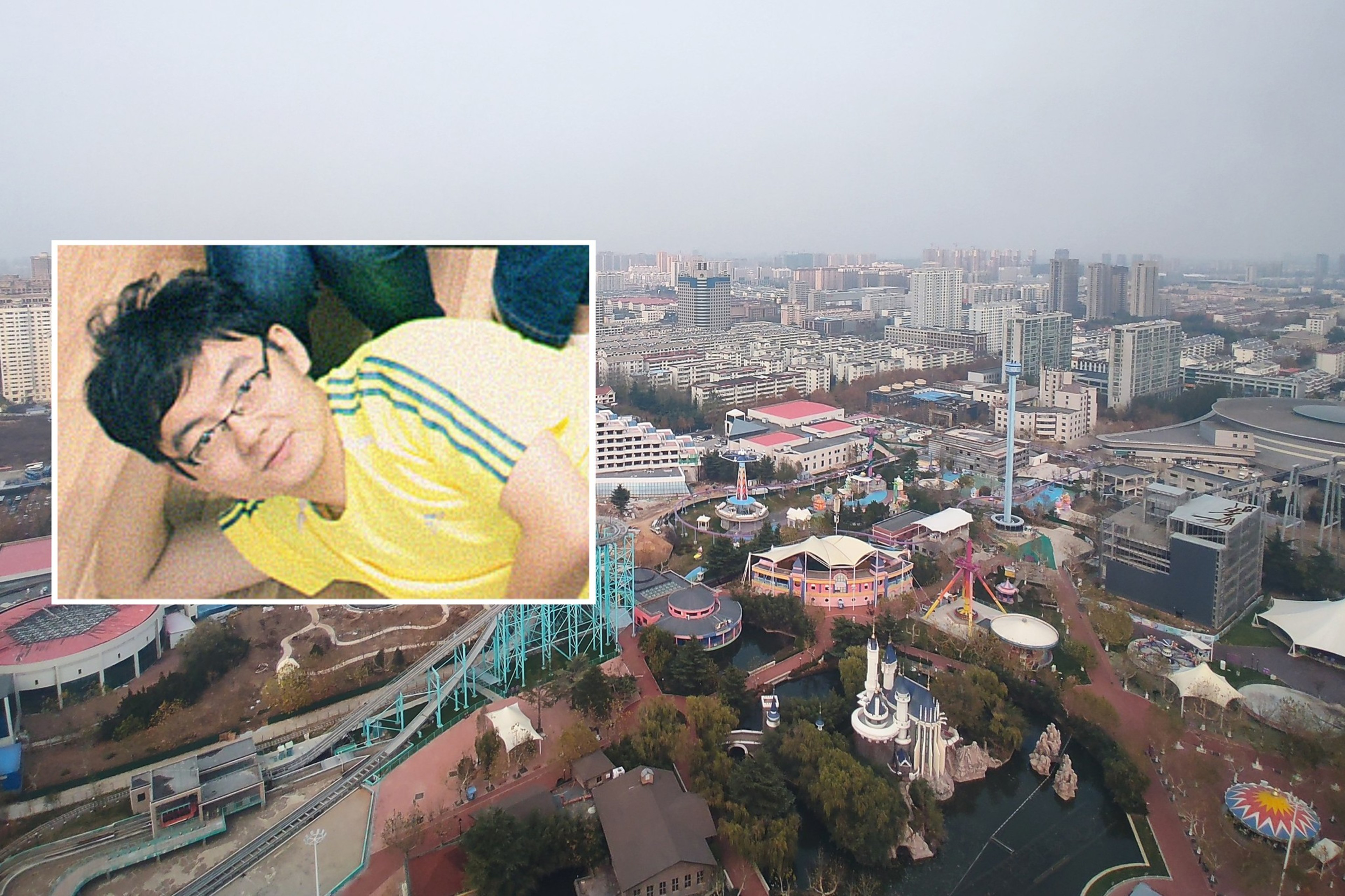 A man wearing glasses and a yellow shirt lies on the floor, overlaid on an aerial view of a city with buildings and an amusement park.