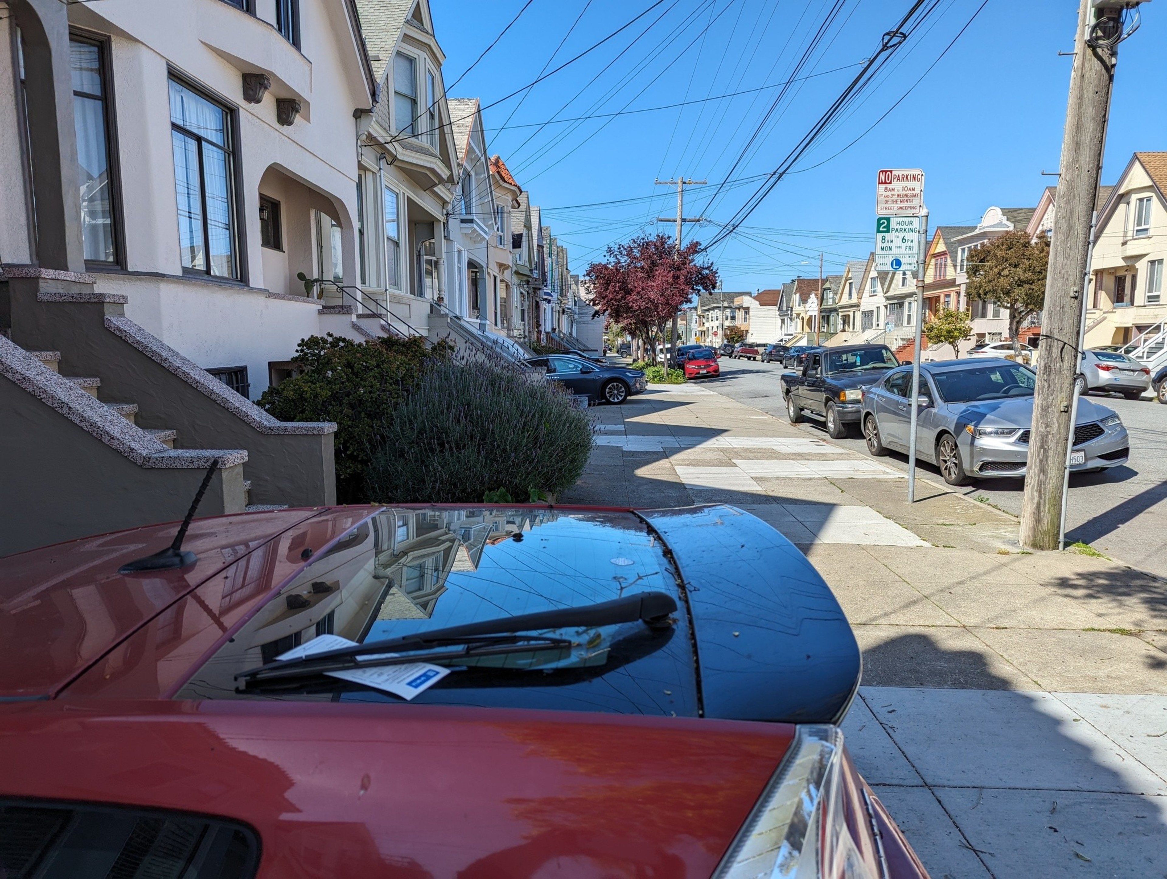 A citation is tucked under the window wiper of a red vehicle parked in a driveway.