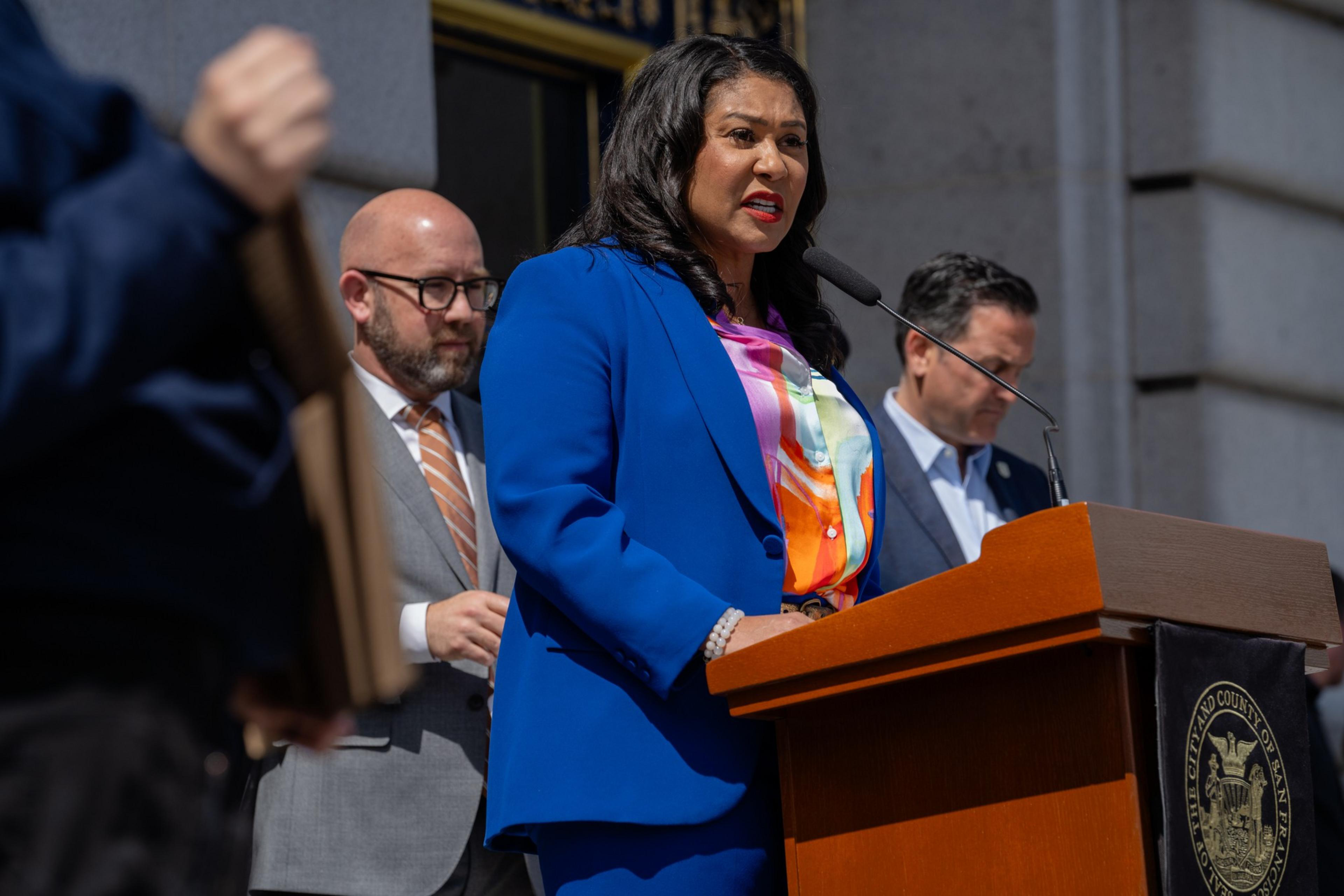 A woman stands at a podium speaking into a microphone.