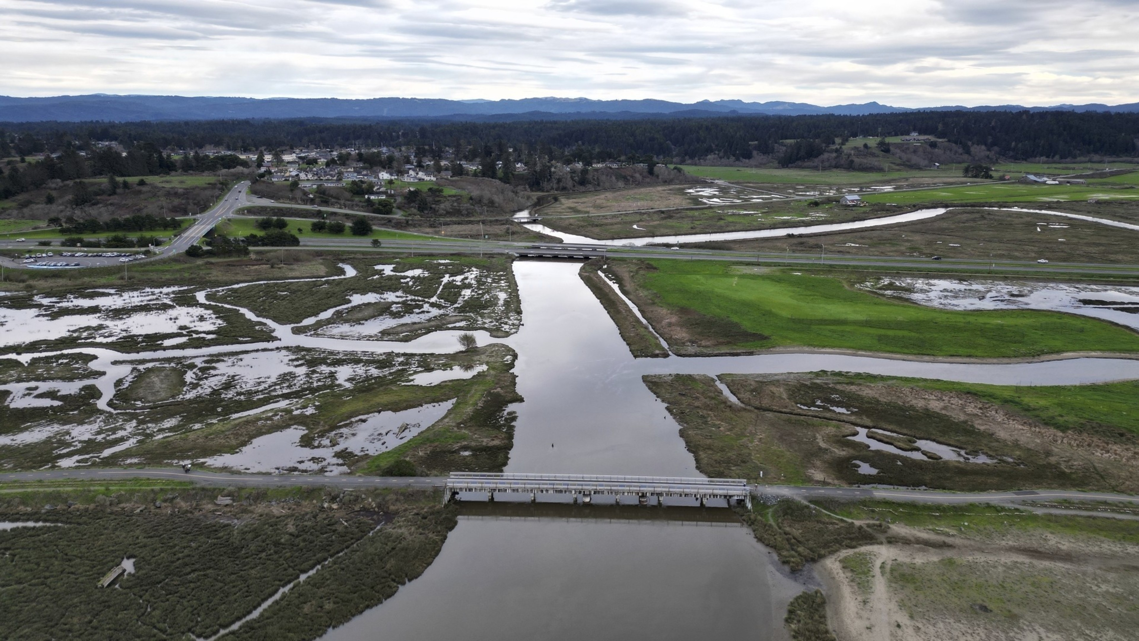 An aerial view of a river and surrounding marshes crisscrossed by roads