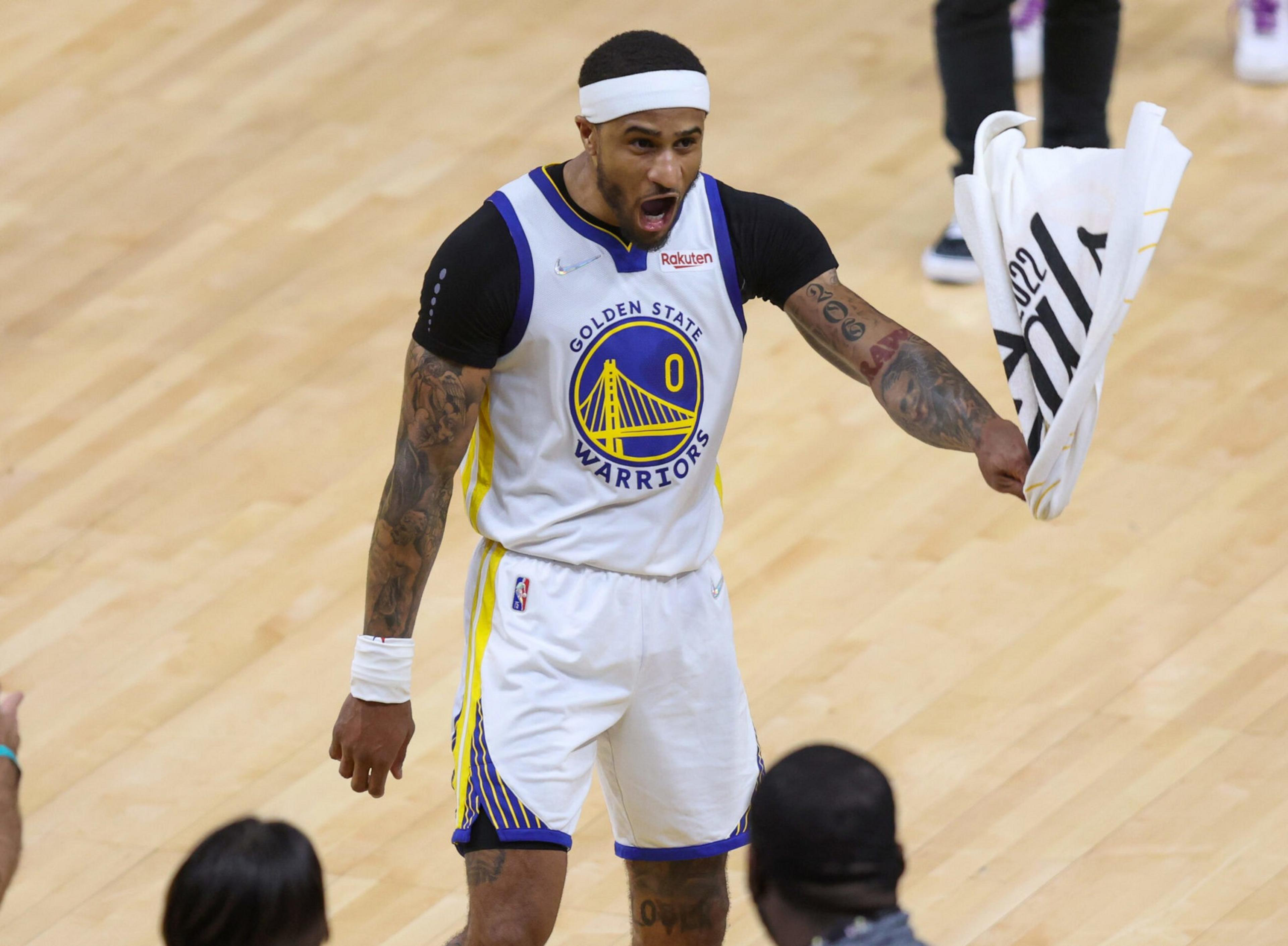 A Golden State Warriors basketball player wearing jersey number 0 is shouting and waving a towel on a basketball court.