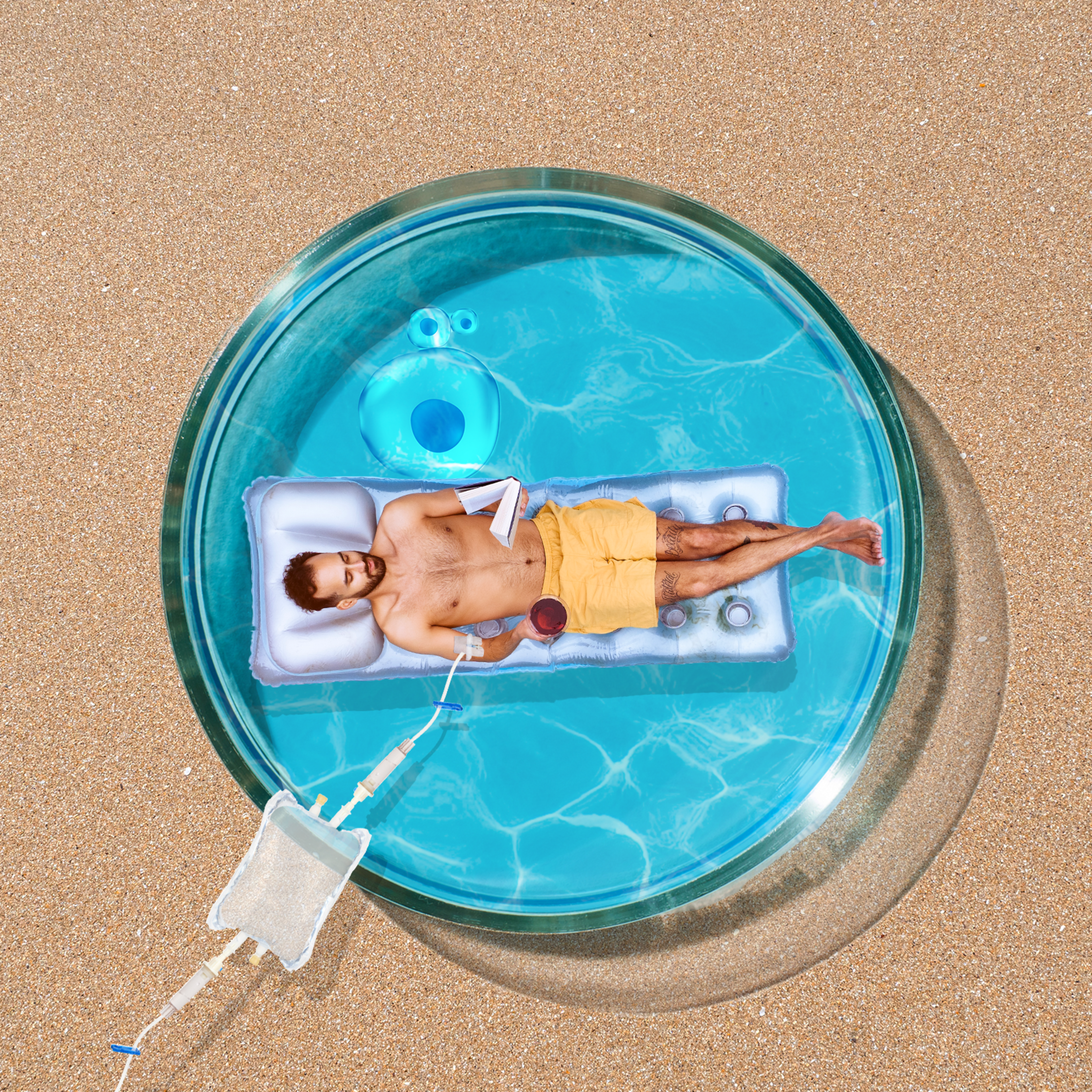 A man relaxes on an inflatable in a small, circular pool on a sandy surface. He holds a drink and a book, wearing yellow shorts under a clear, sunny sky.