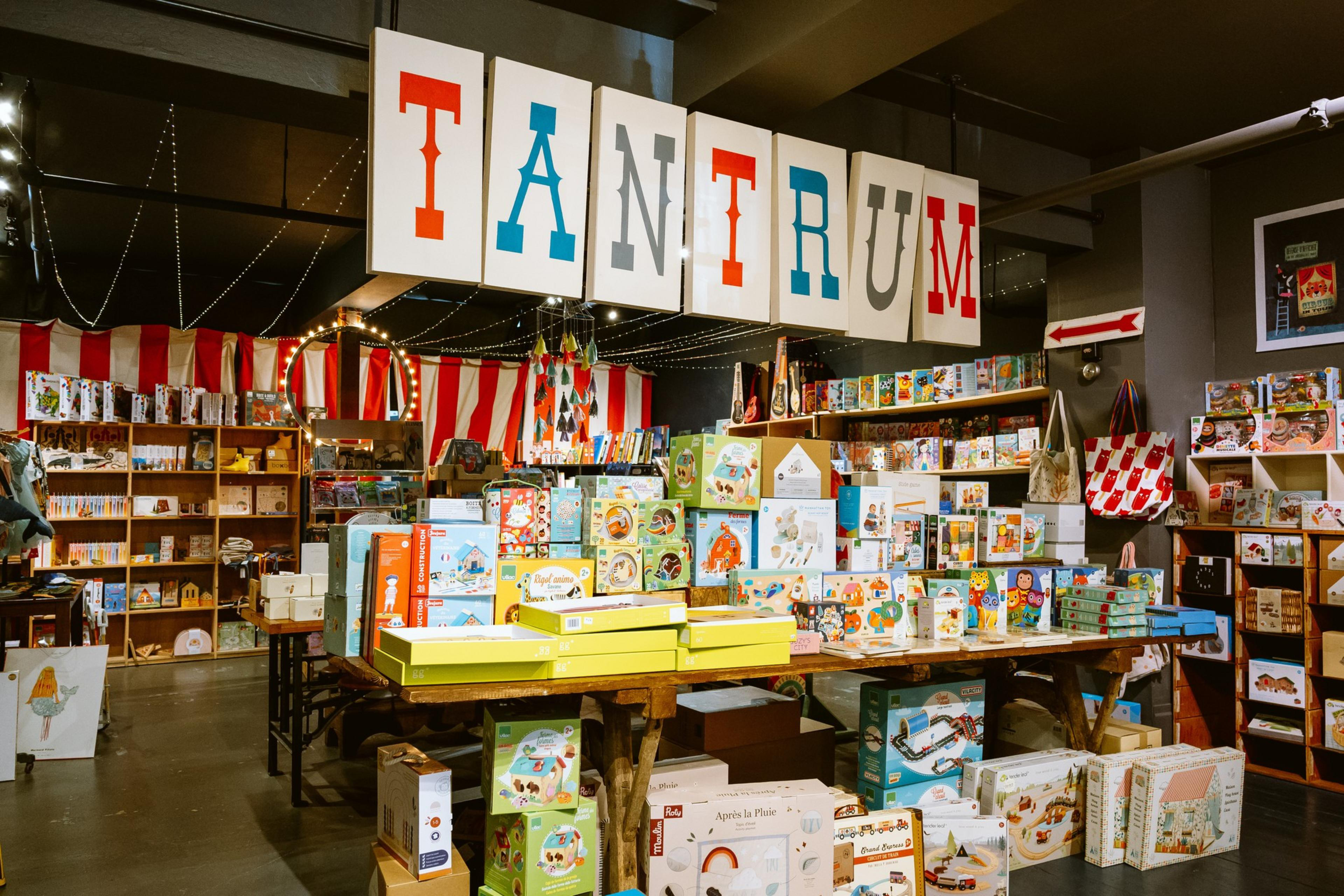 A display of toys and games at Tantrum children's store beneath a store sign. 