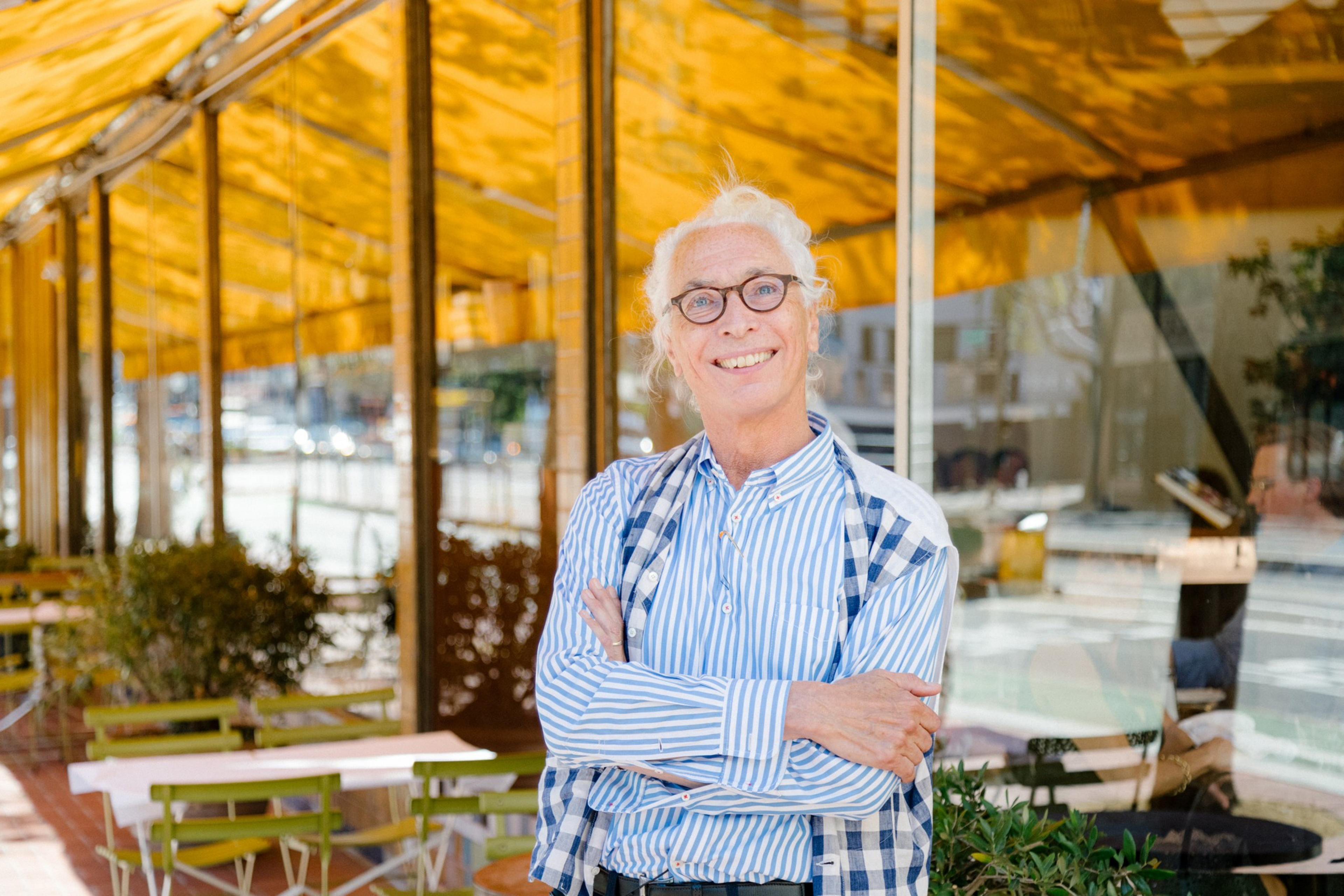 A person smiles for a portrait outside over an awning area at a restaurant.