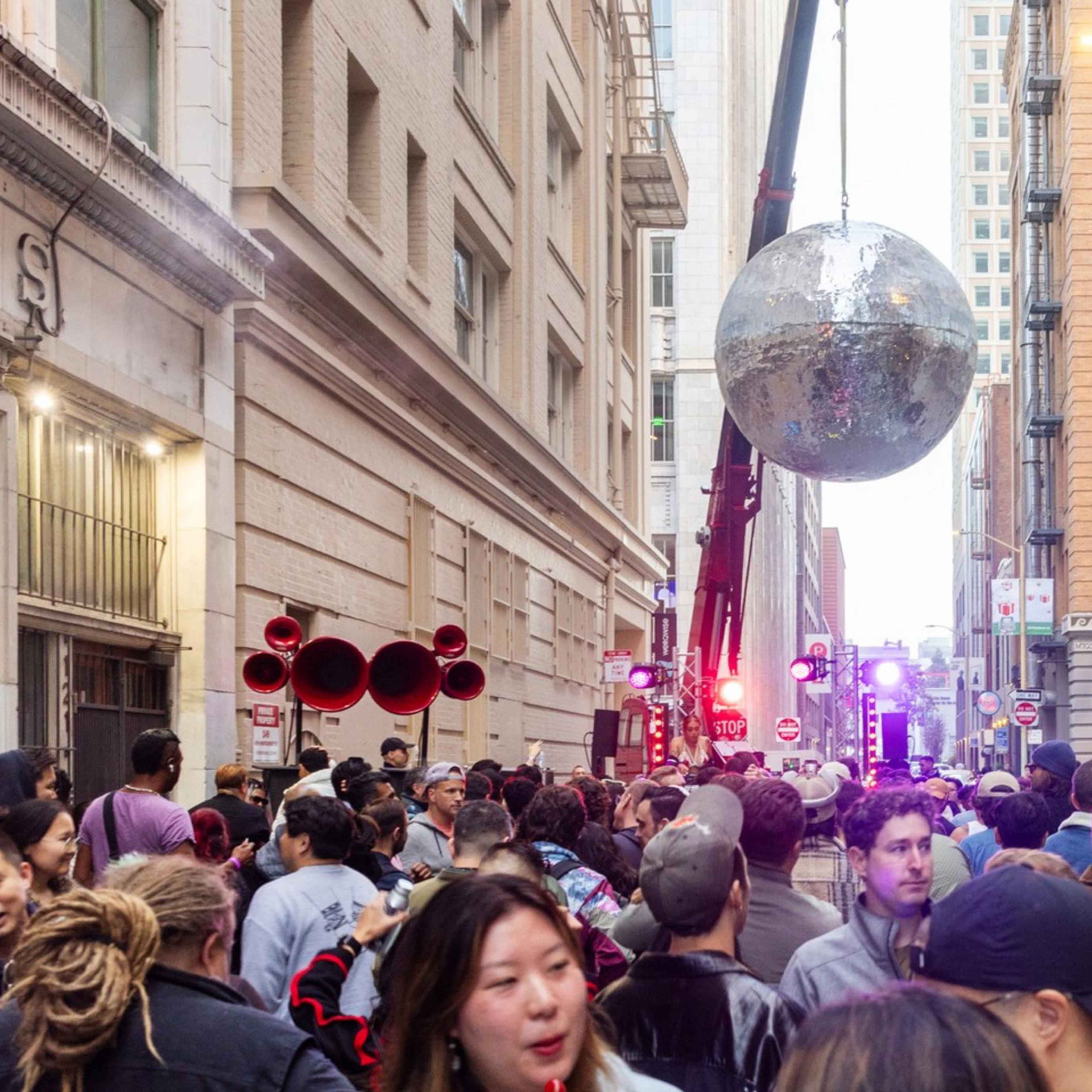 A crowd gathers under a giant hanging disco ball.
