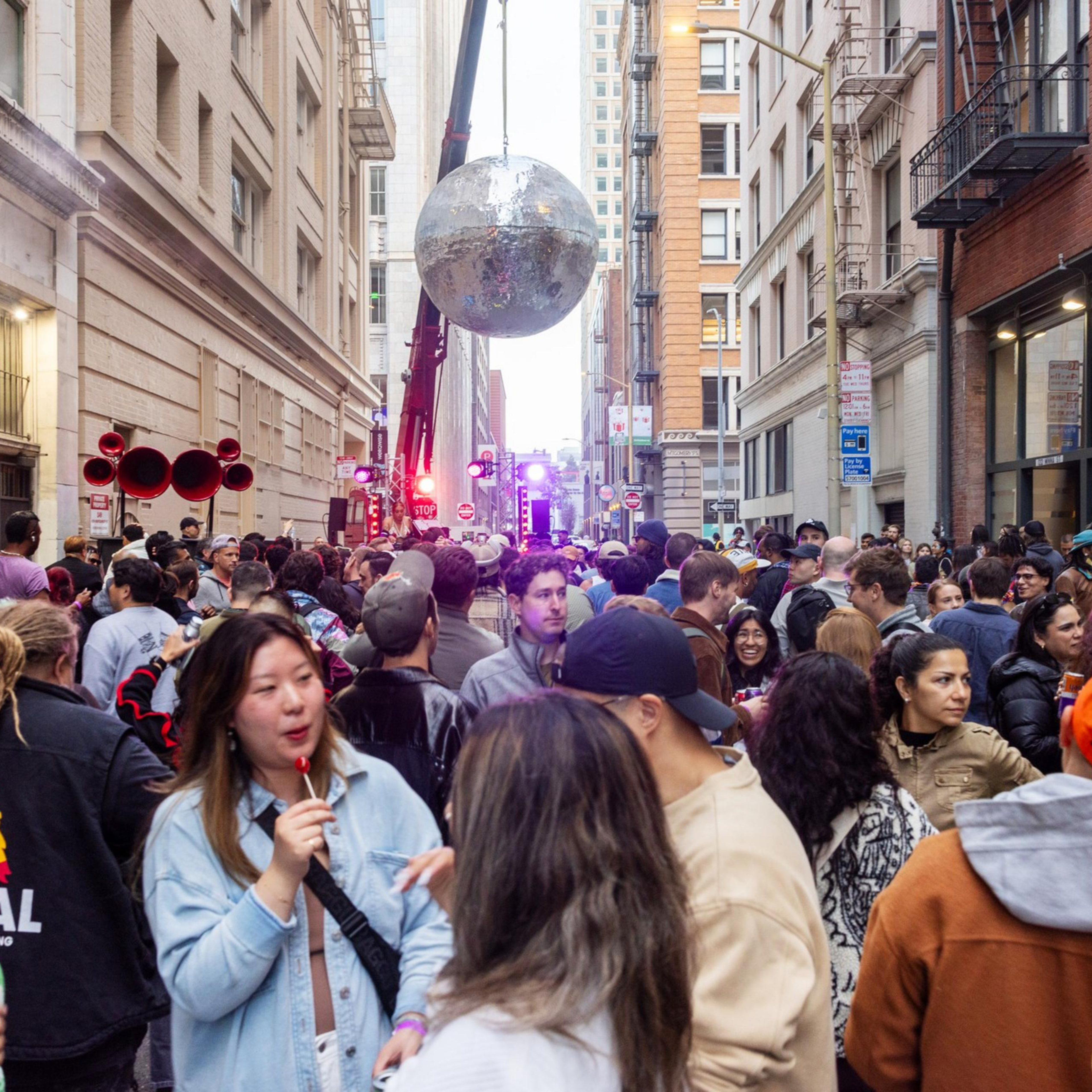 A crowd gathers under a giant hanging disco ball.