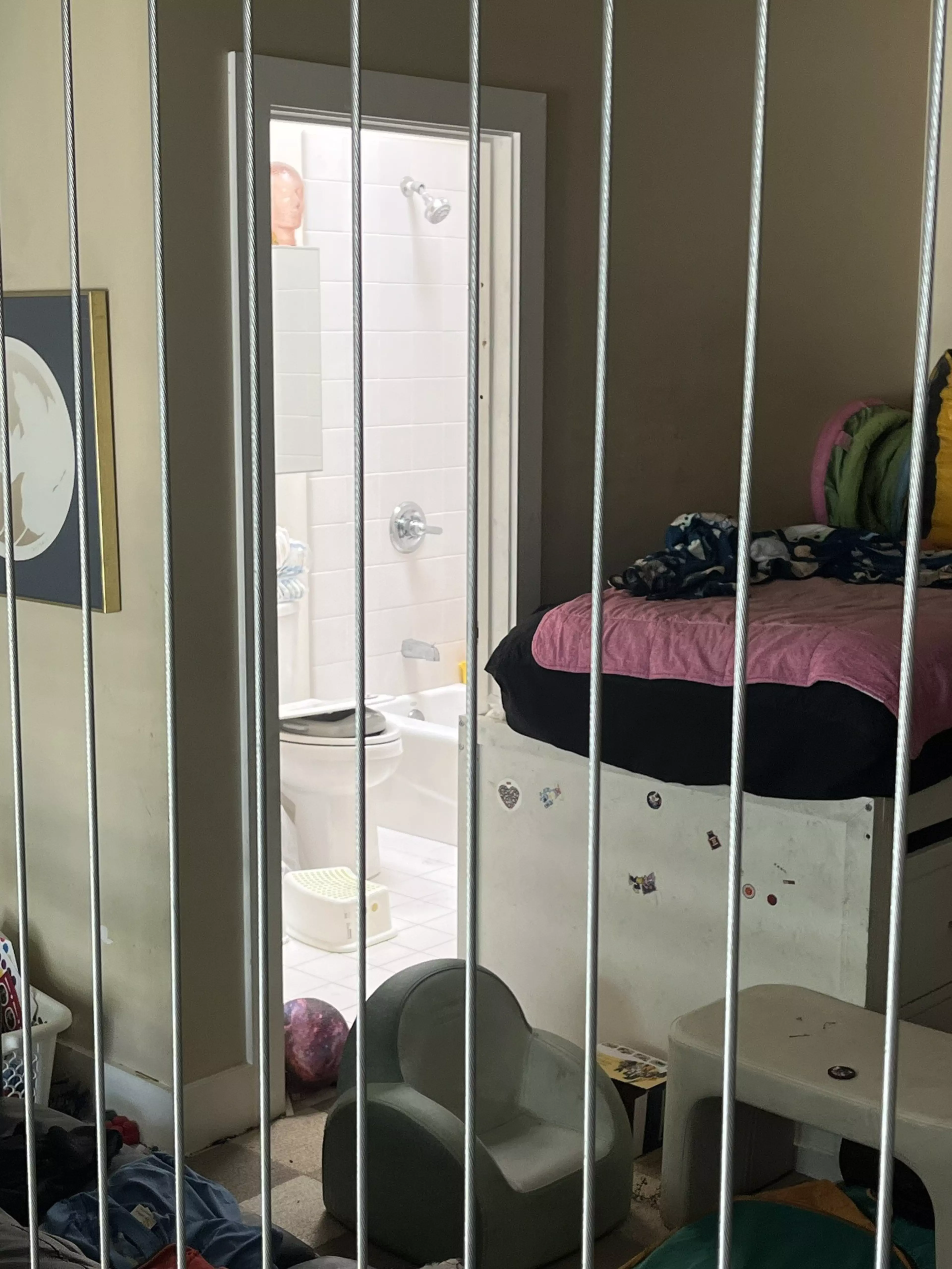 Mała sypialnia z łóżkiem nakrytym różowym kocem, obok łazienki; obok łóżka stoi zielony fotel dziecięcy i biały stołek.