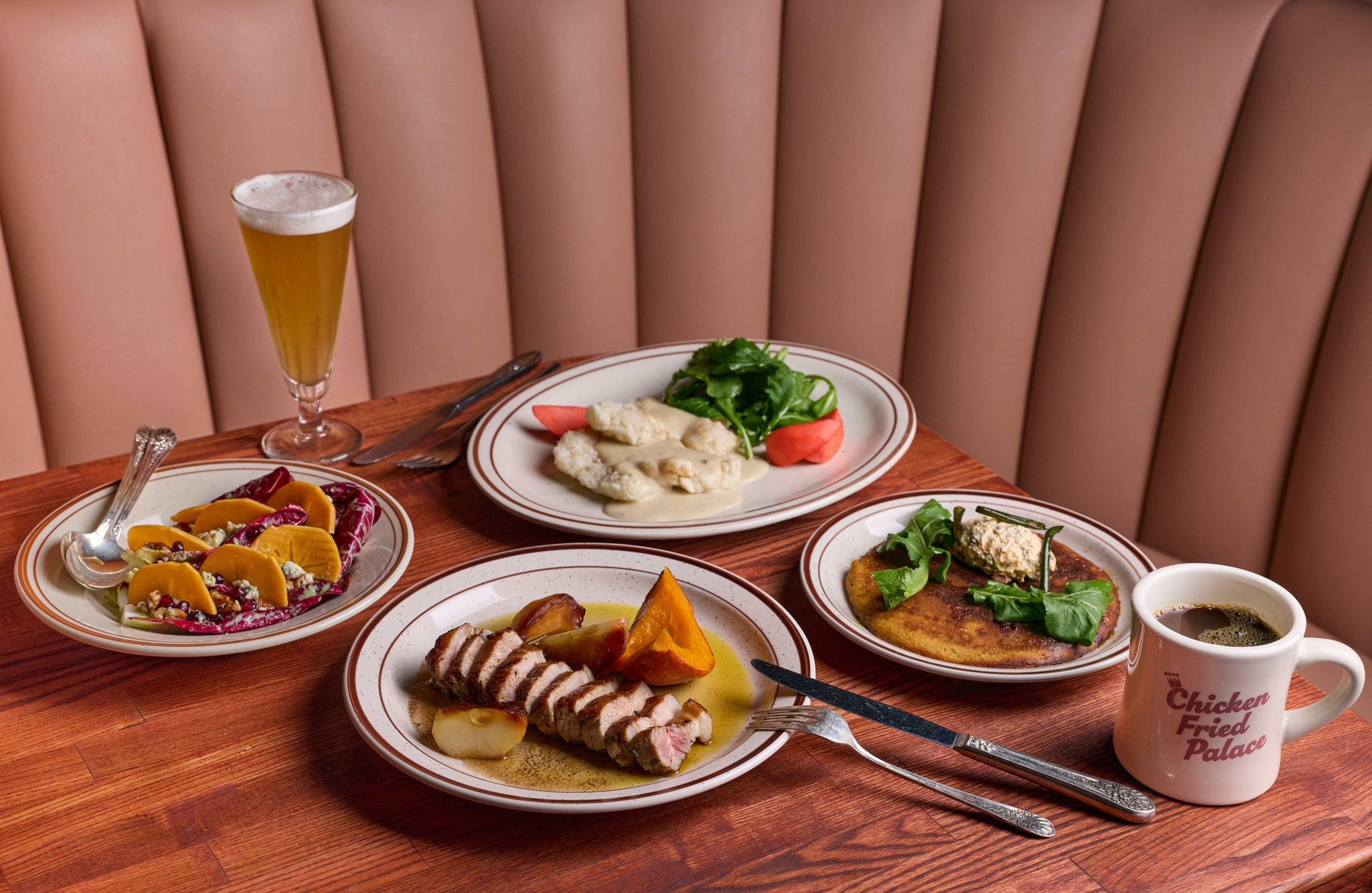 Grilled meat with sauce and vegetables, creamy dish with salad, flatbread with greens and spread, a plate of tacos, a mug of coffee, and a glass of beer on a wooden table.