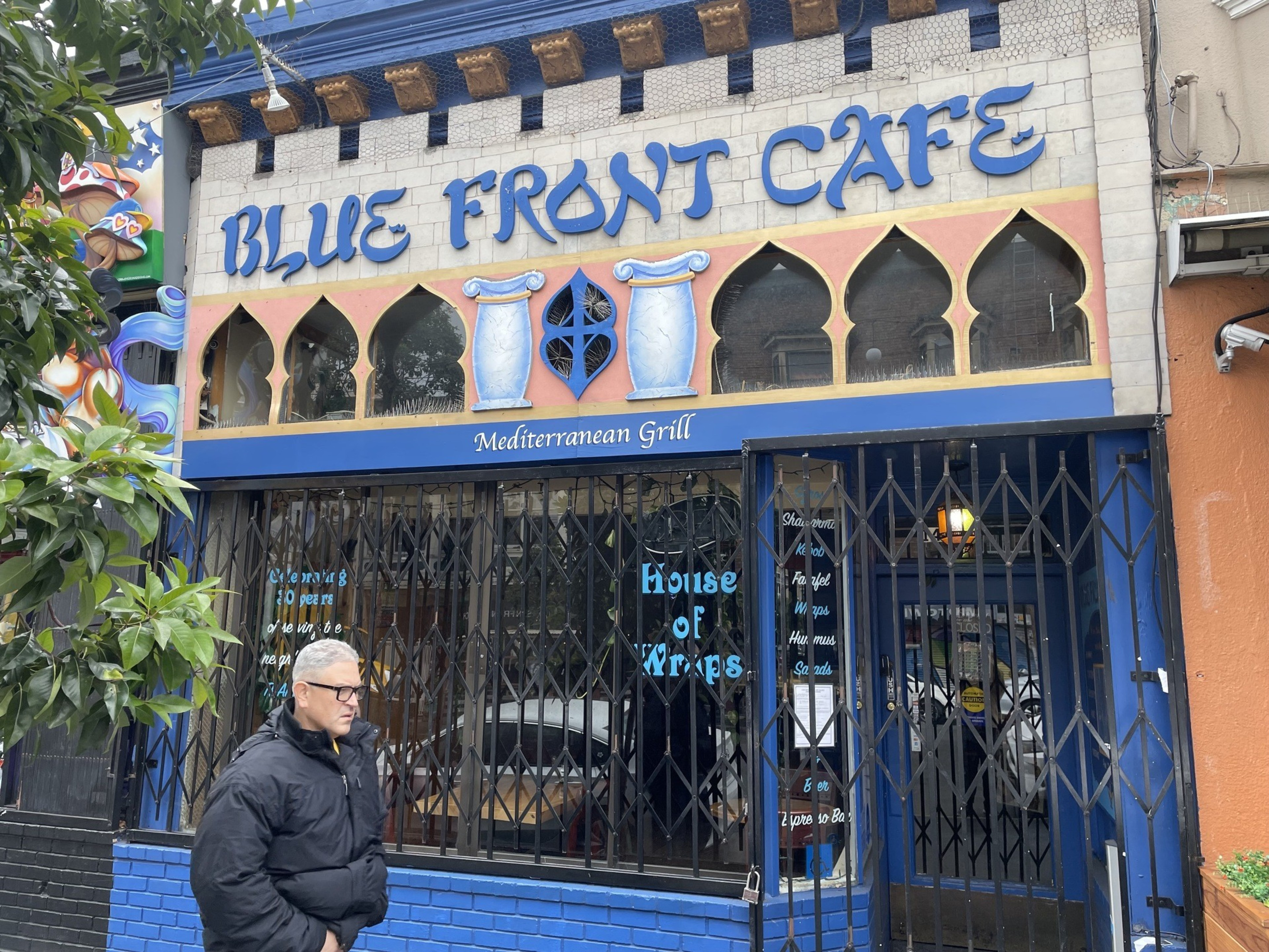 A man walks in front of a restaurant.