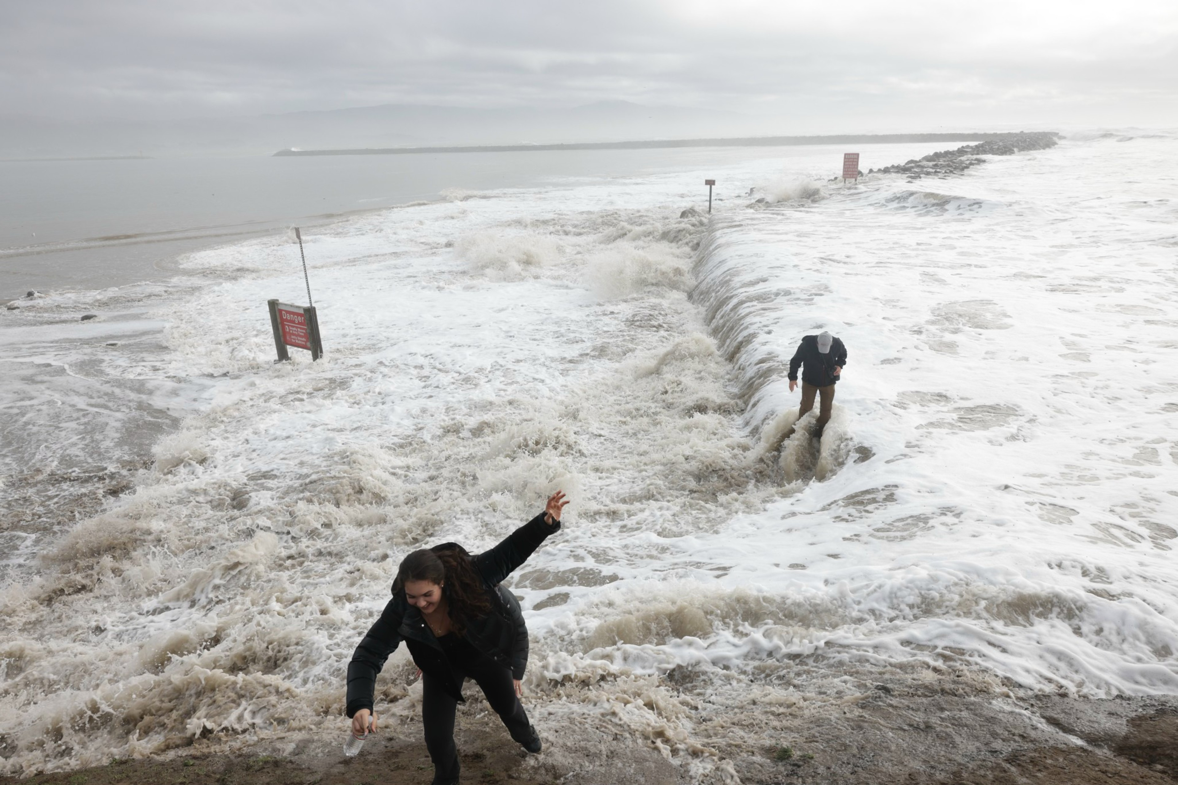 Two people get caught in the waves along the beach in Pacifica.