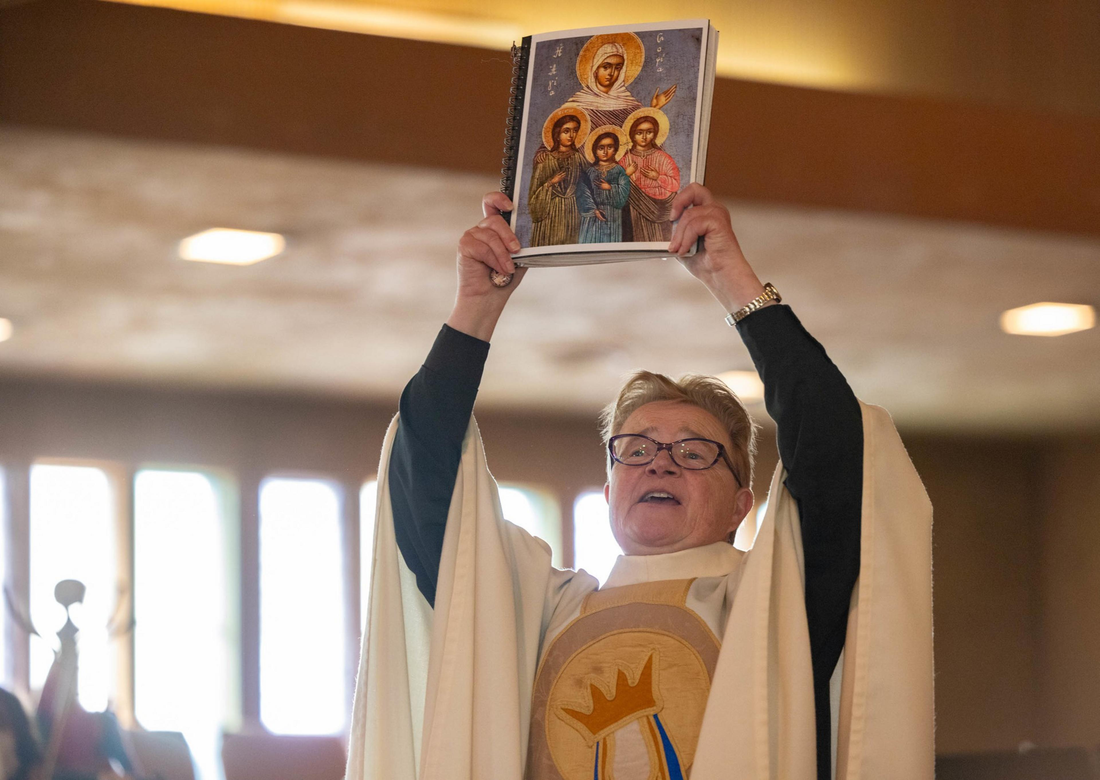 A pastors holds a book up with both hands during a church service.