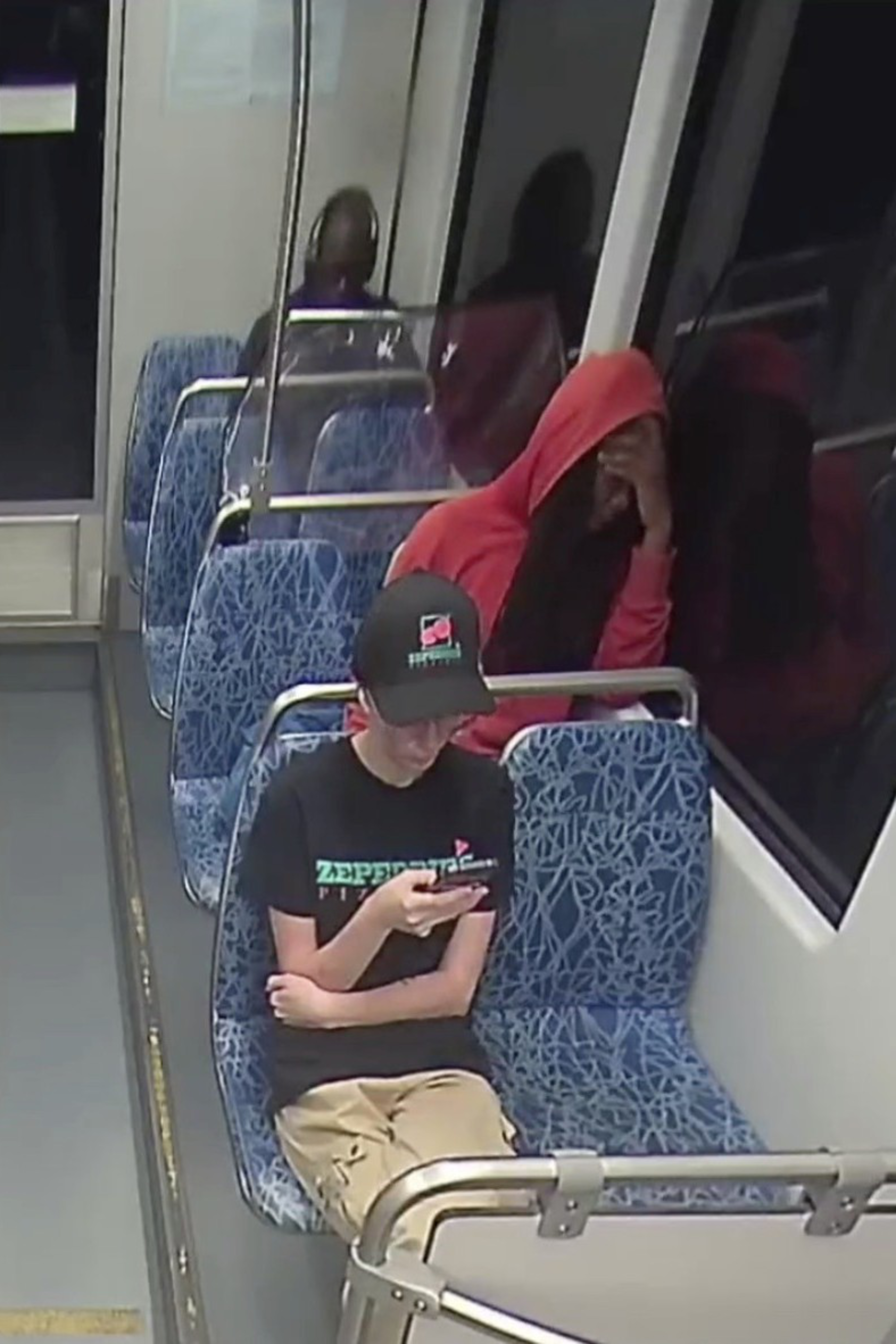 Five passengers sit spread out on a nearly empty bus, each focused on their phones, with some resting their heads on their hands or seats.