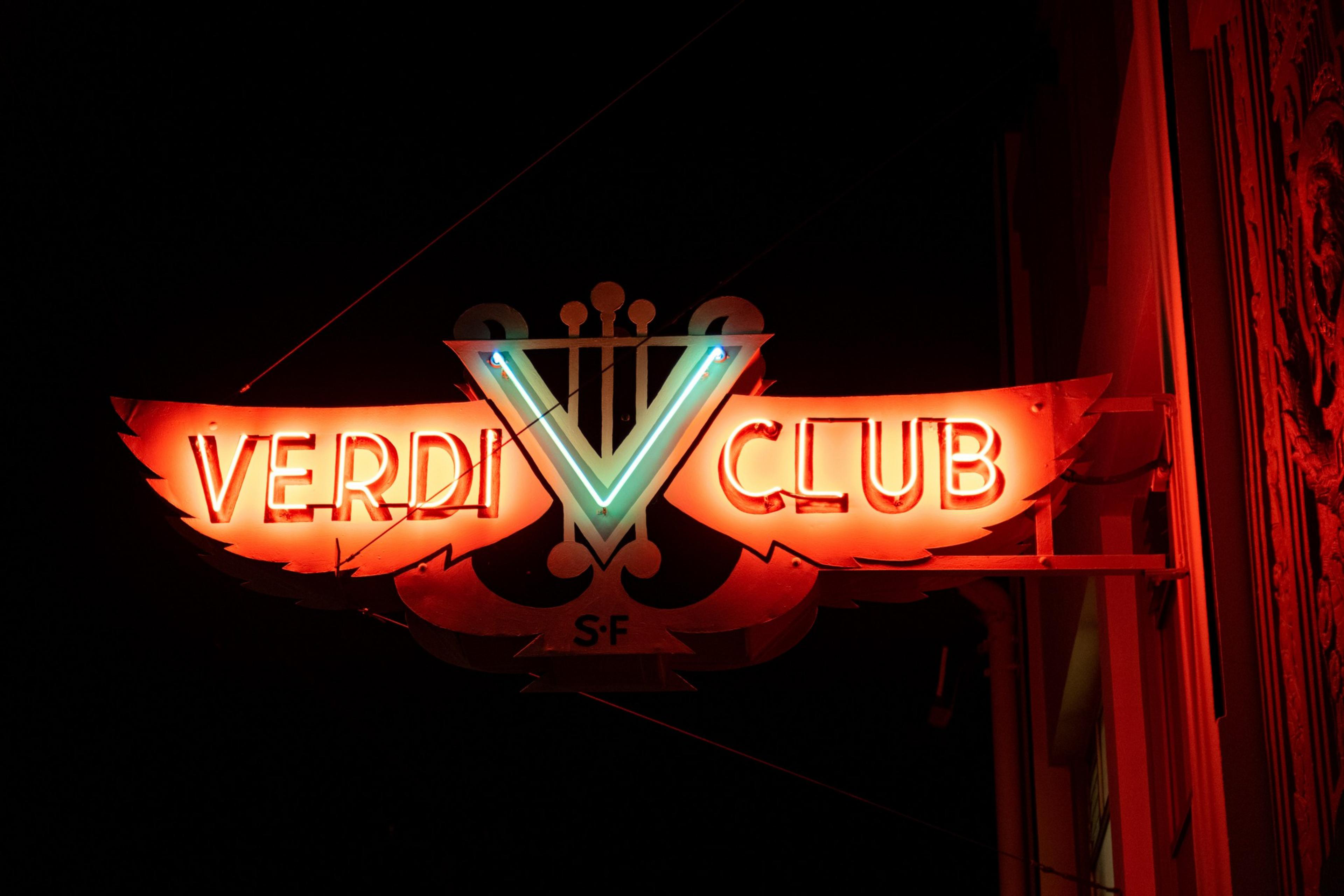 A red neon sign at night that reads &quot;VERDI CLUB&quot;