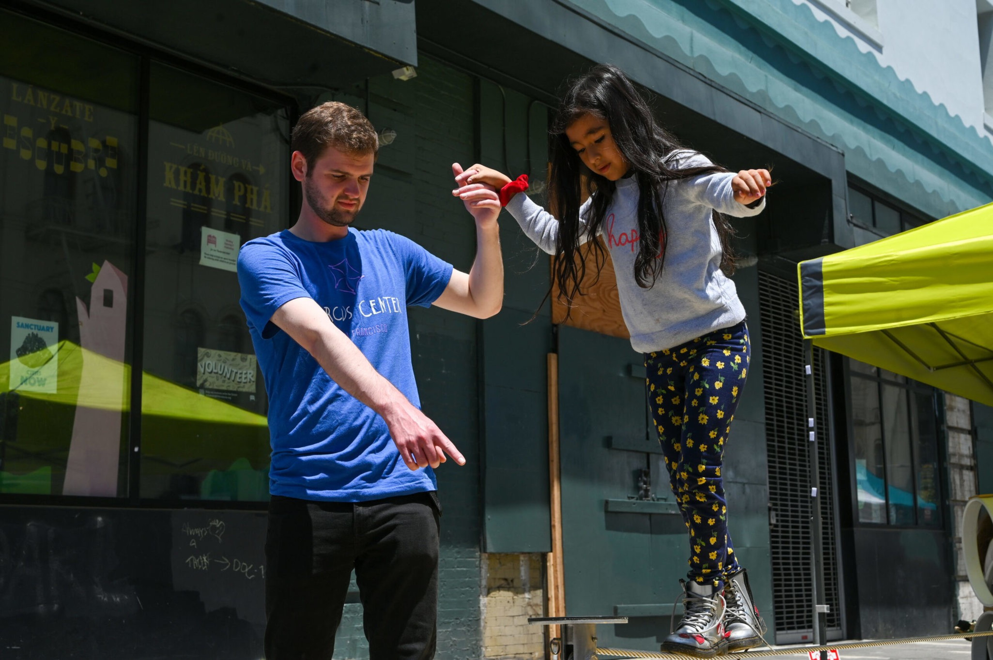 A man assists a girl with her balance.