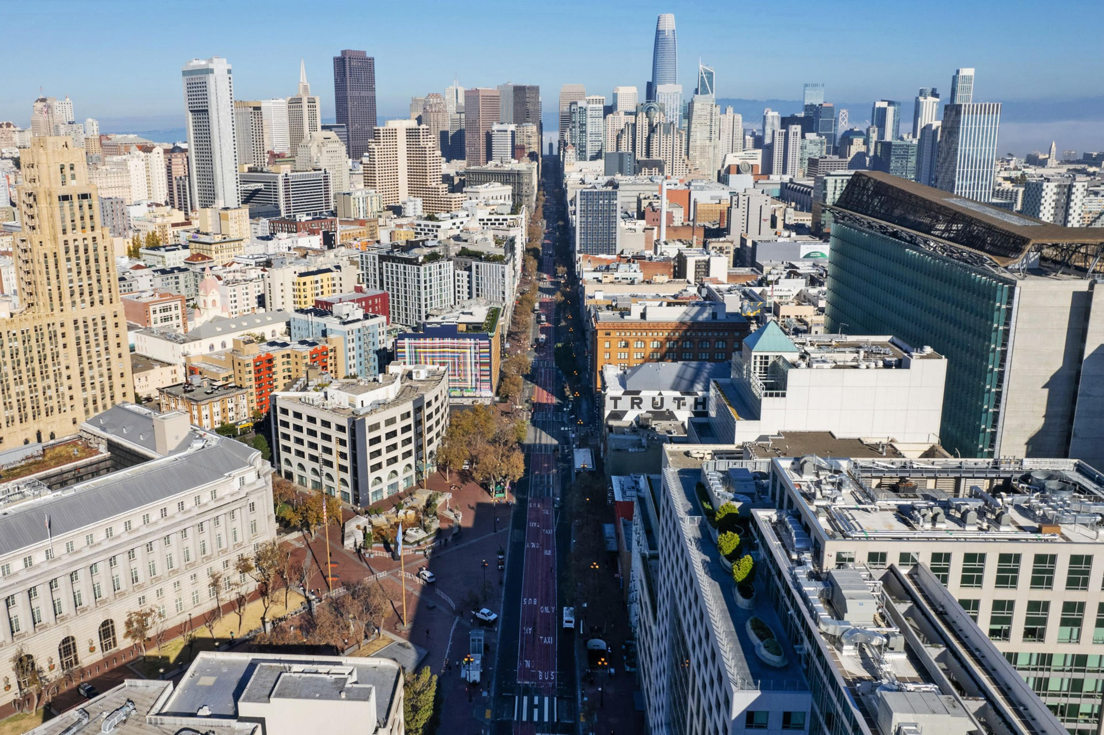 Aerial view of a dense urban cityscape with a mix of high-rise buildings and a clear sky.