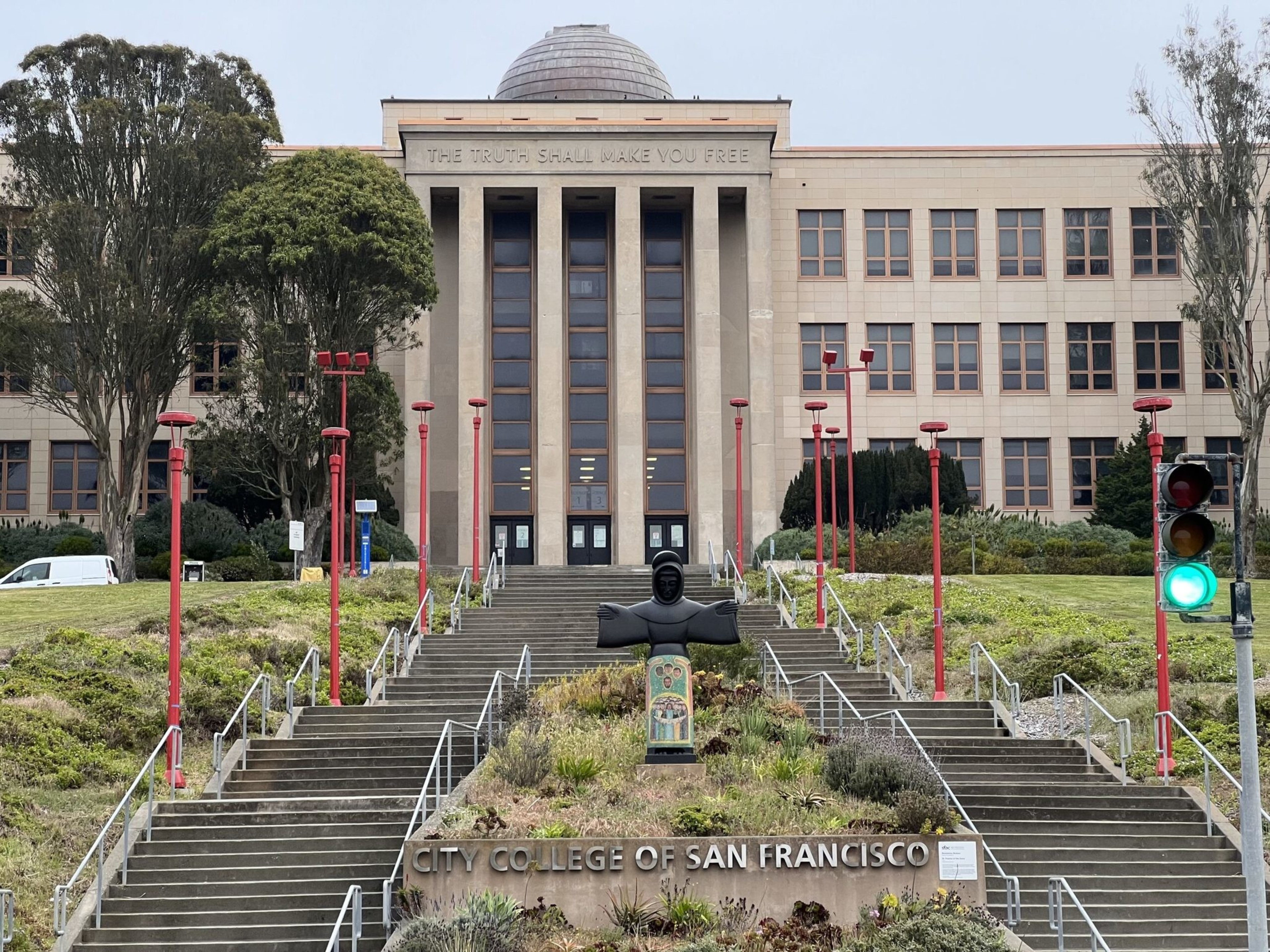 A large building with tall columns displays "THE TRUTH SHALL MAKE YOU FREE" above the entrance and "CITY COLLEGE OF SAN FRANCISCO" below the stairs.