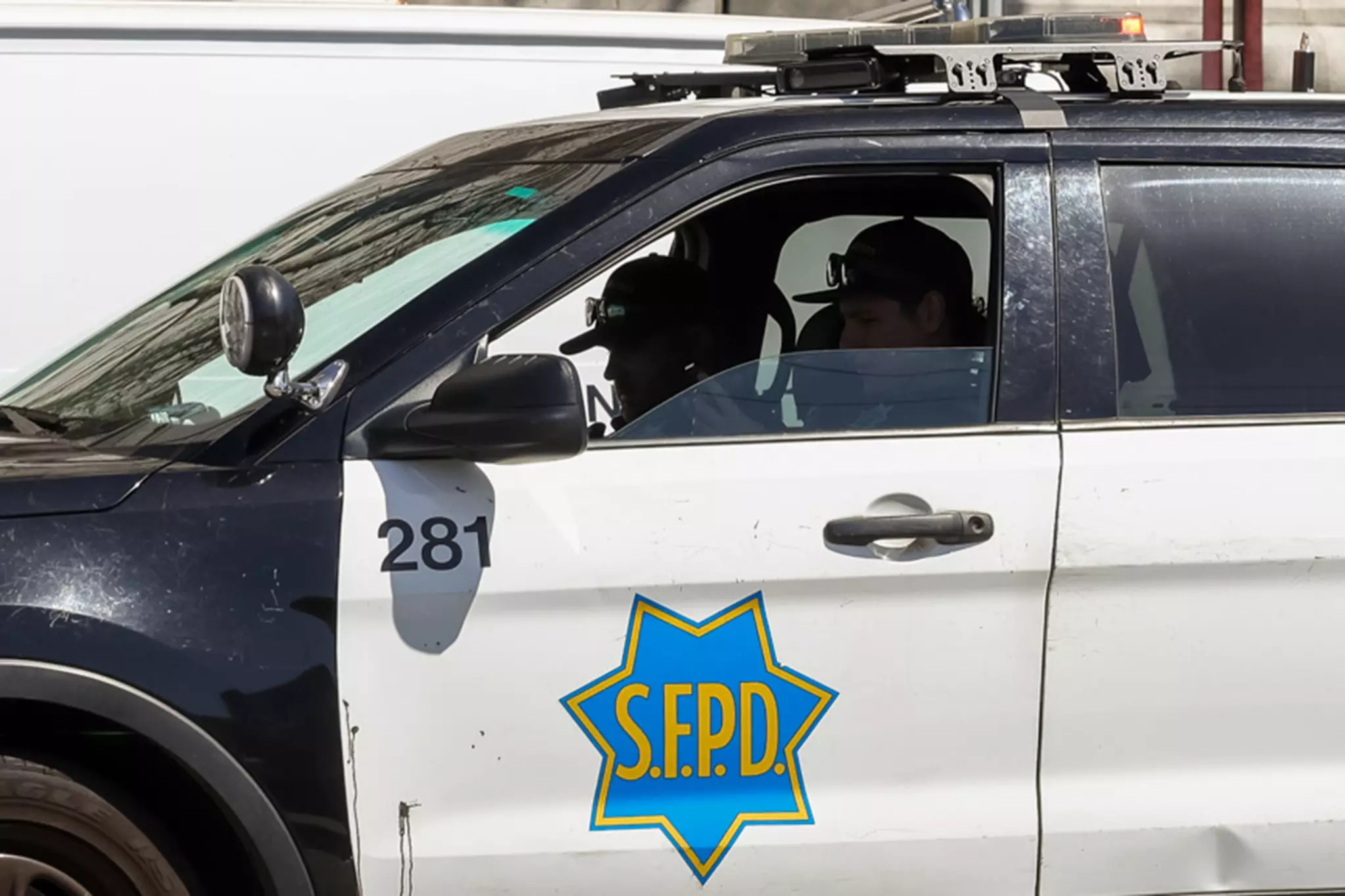 A police car with two officers inside; emblem reads "S.F.P.D." on the door.