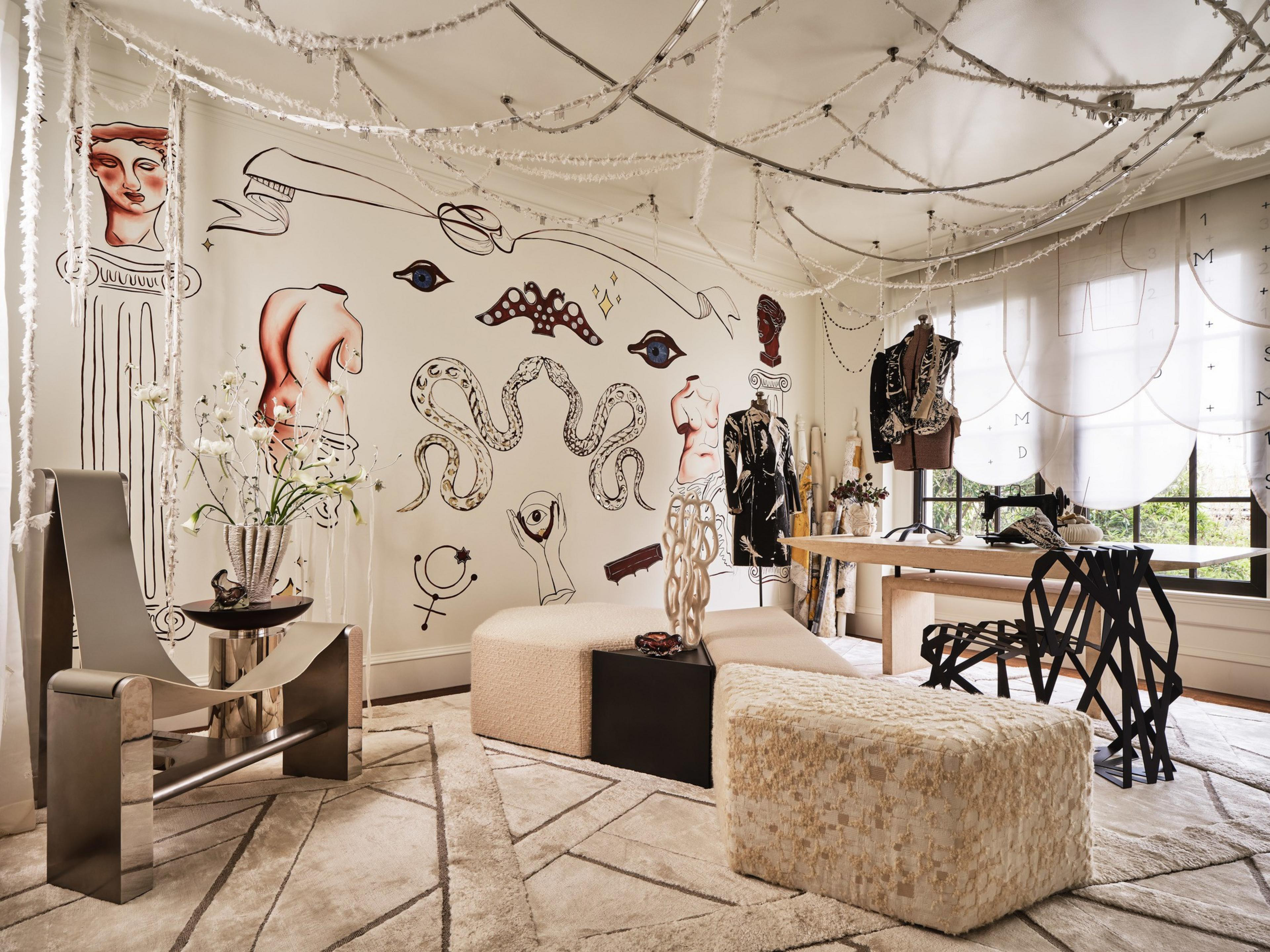 Modern artistic room with abstract wall murals, sculptural furniture, a minimalist metal chair, curved beige seating, and mannequins dressed in stylish clothing.