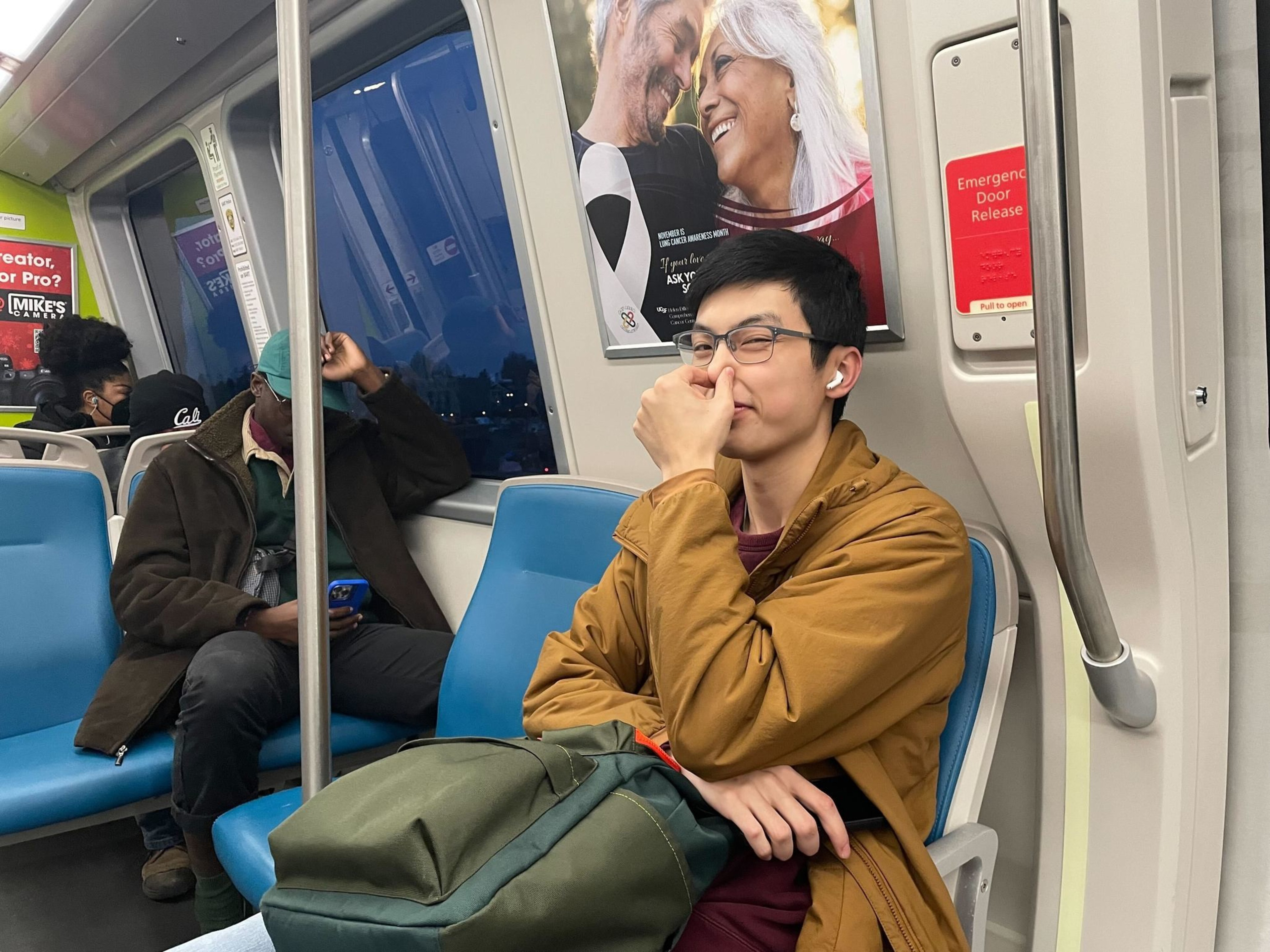 BART passenger Alvin Wong pinches his nose on a train heading from 12th St. station towards West Oakland station.