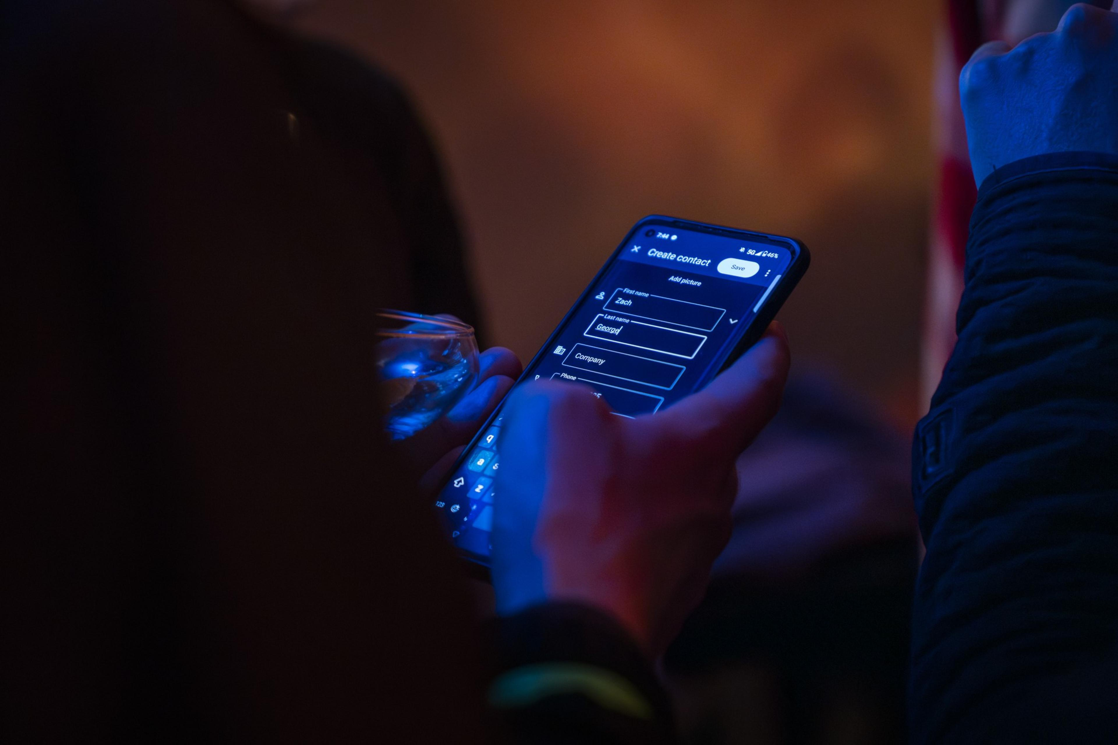 A person holds a phone to input someone's contact number.