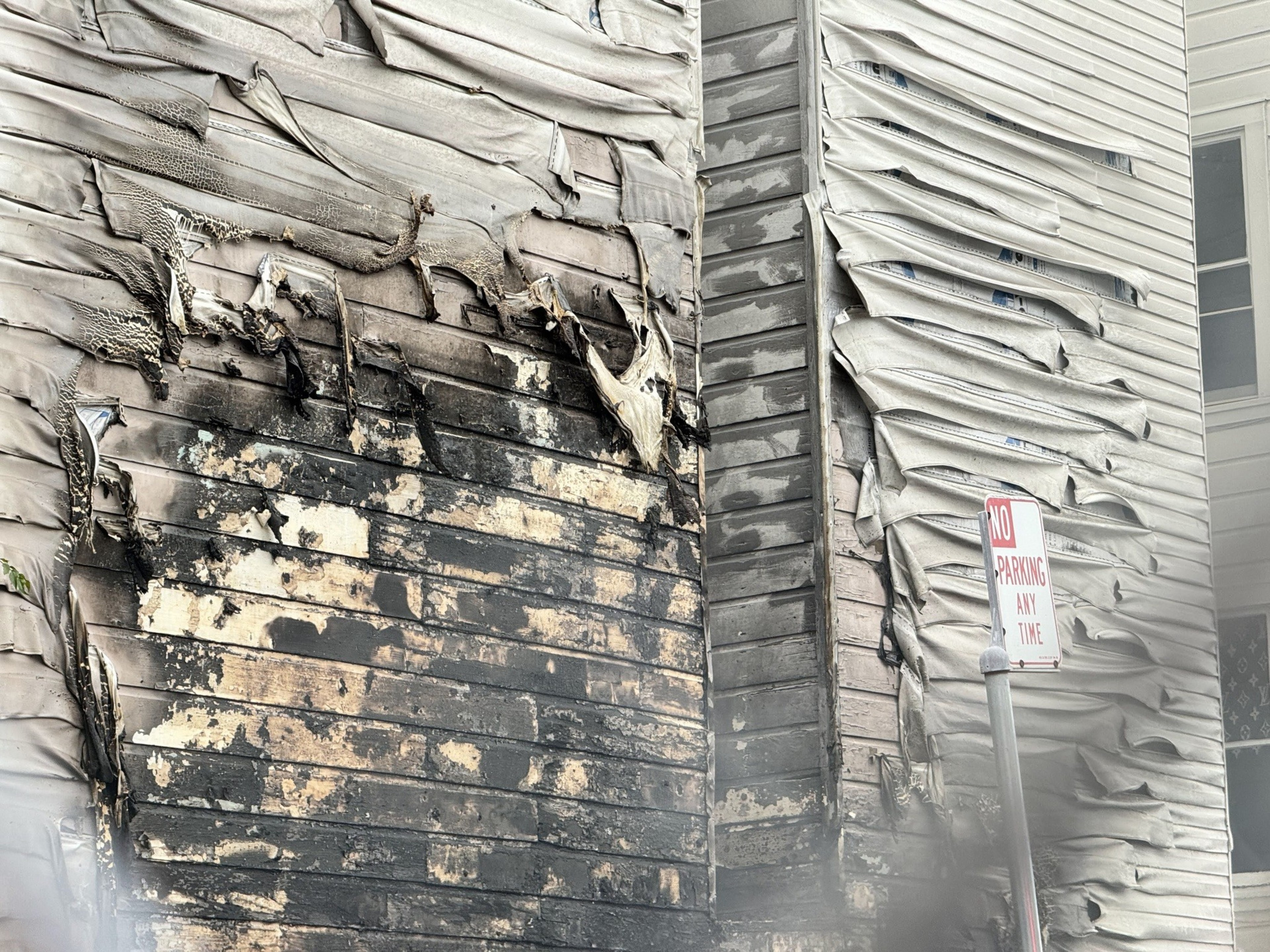 Damage to the side of a residential building after two cars were set on fire at a parking lot off Boardman Place on Jan. 2, 2024.