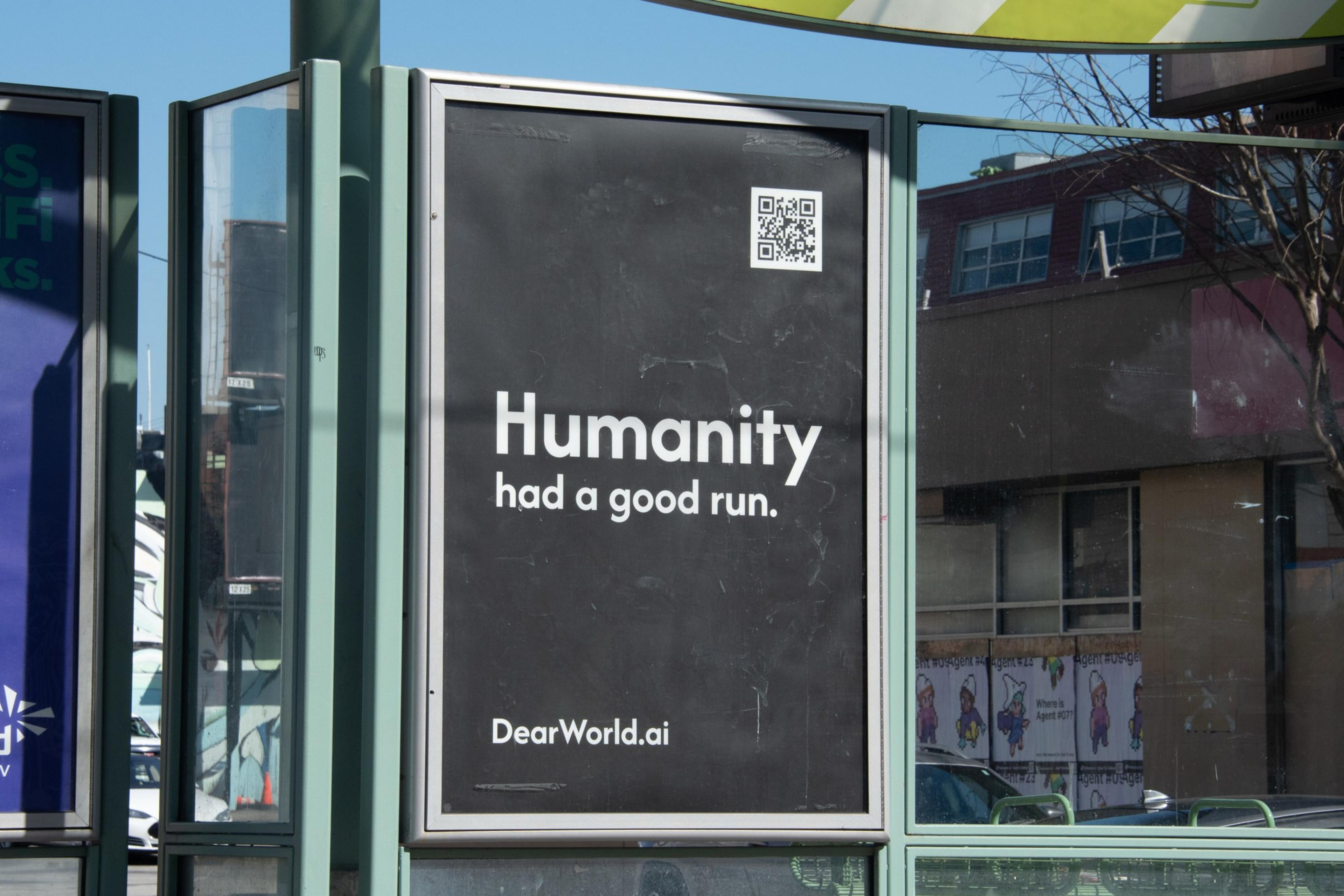 A black poster with white text reads, "Humanity had a good run." and includes a QR code and the website DearWorld.ai.