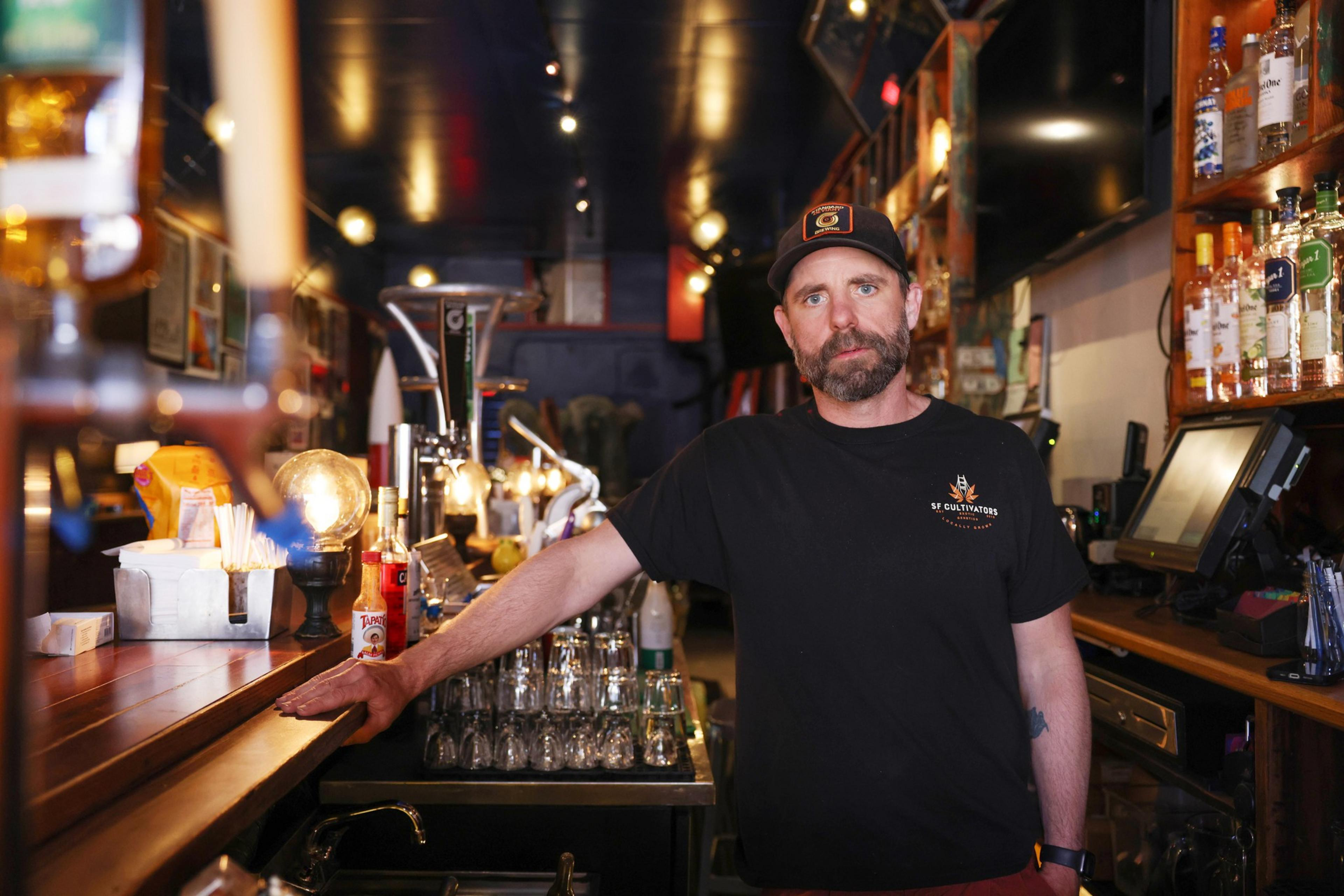 A man wearing black shirt stands at a bar.