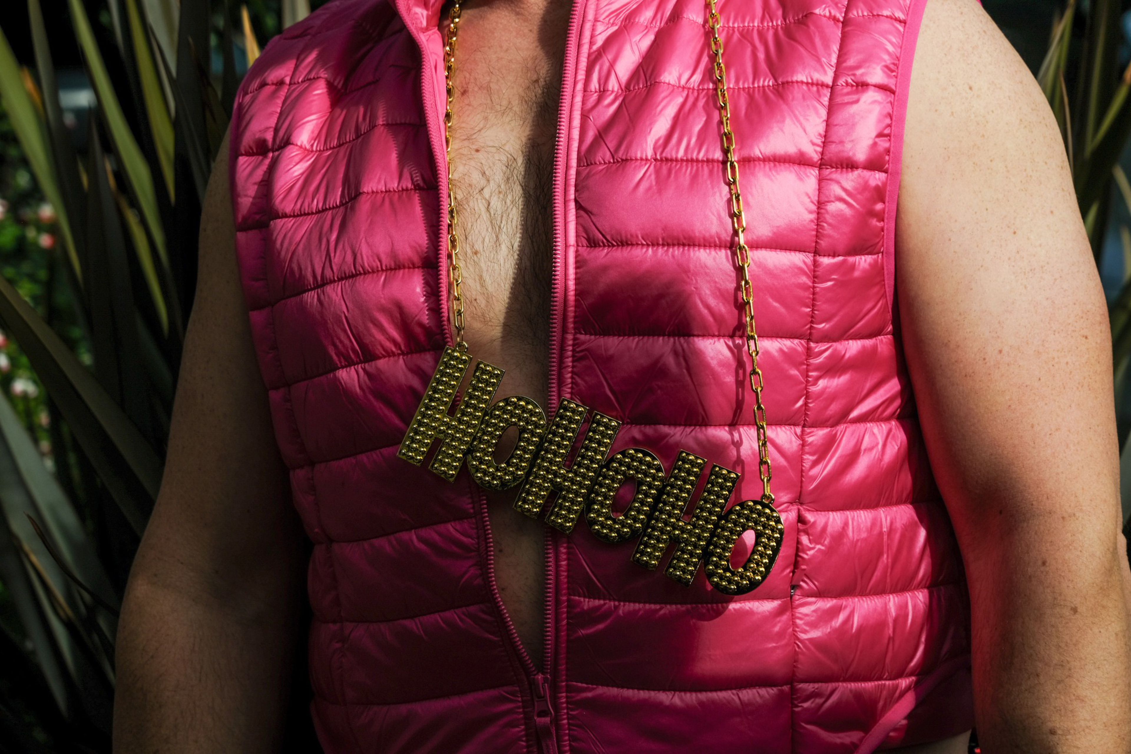 A person wears a gold necklace that reads that reads HoHoHo