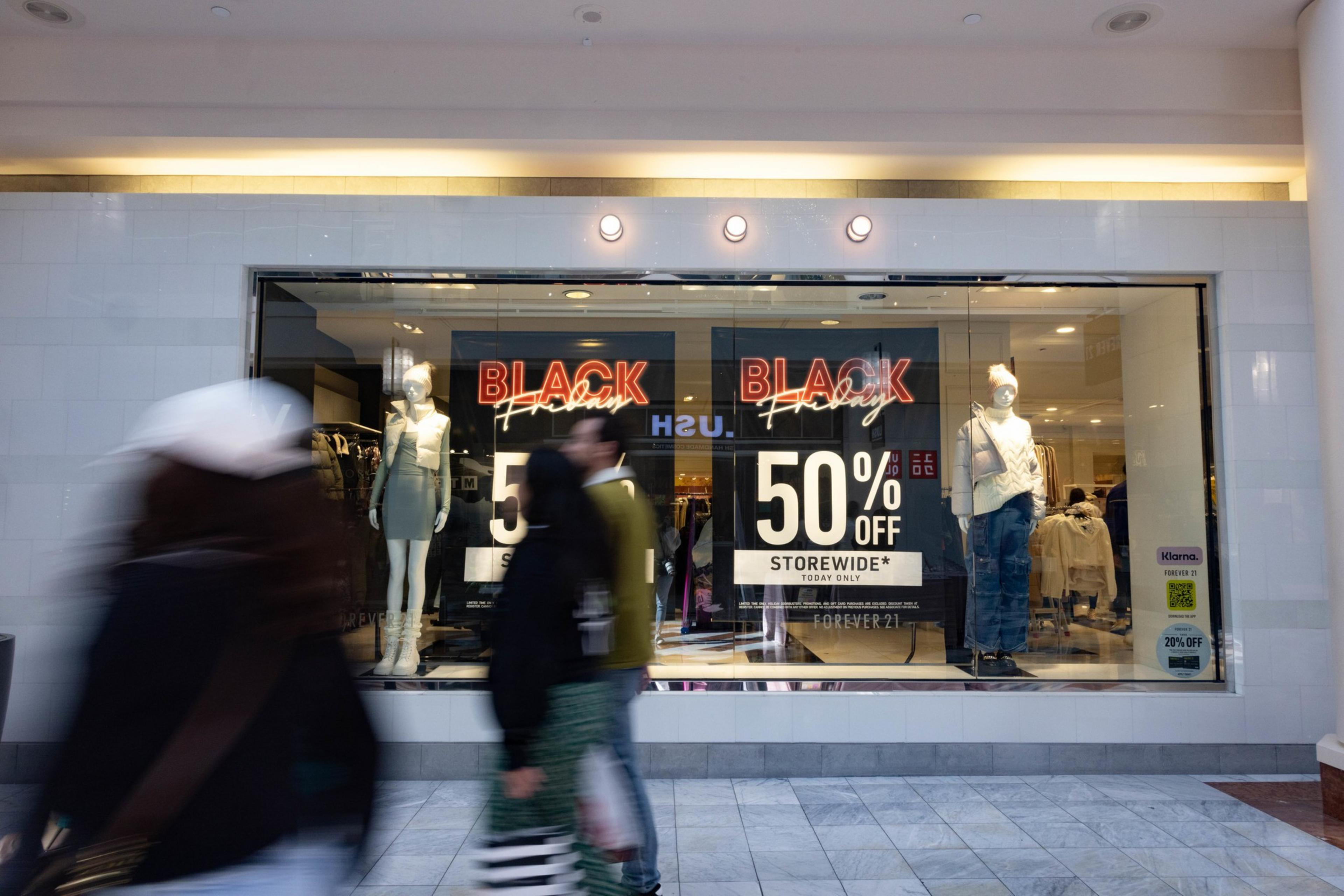 People walk by Black Friday signs in Stonestown Galleria.