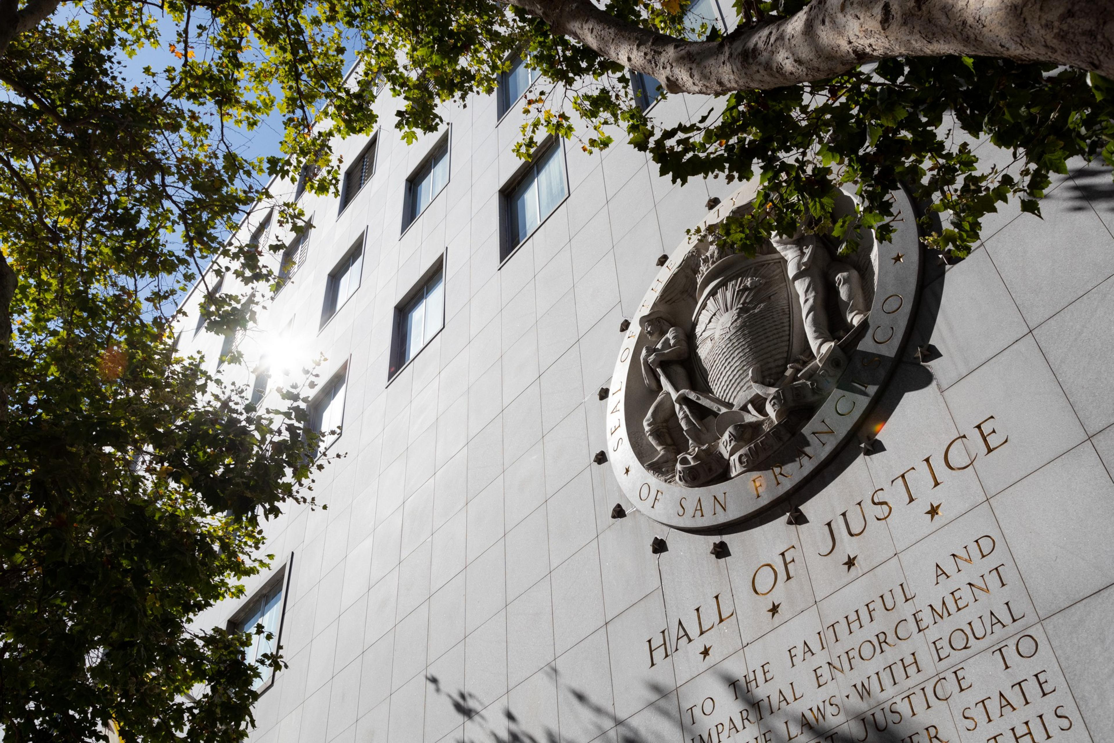 The exterior of a building with a large circular seal that reads &quot;Seal of the City of San Francisco&quot; and under that read &quot;Hall of Justice&quot;.