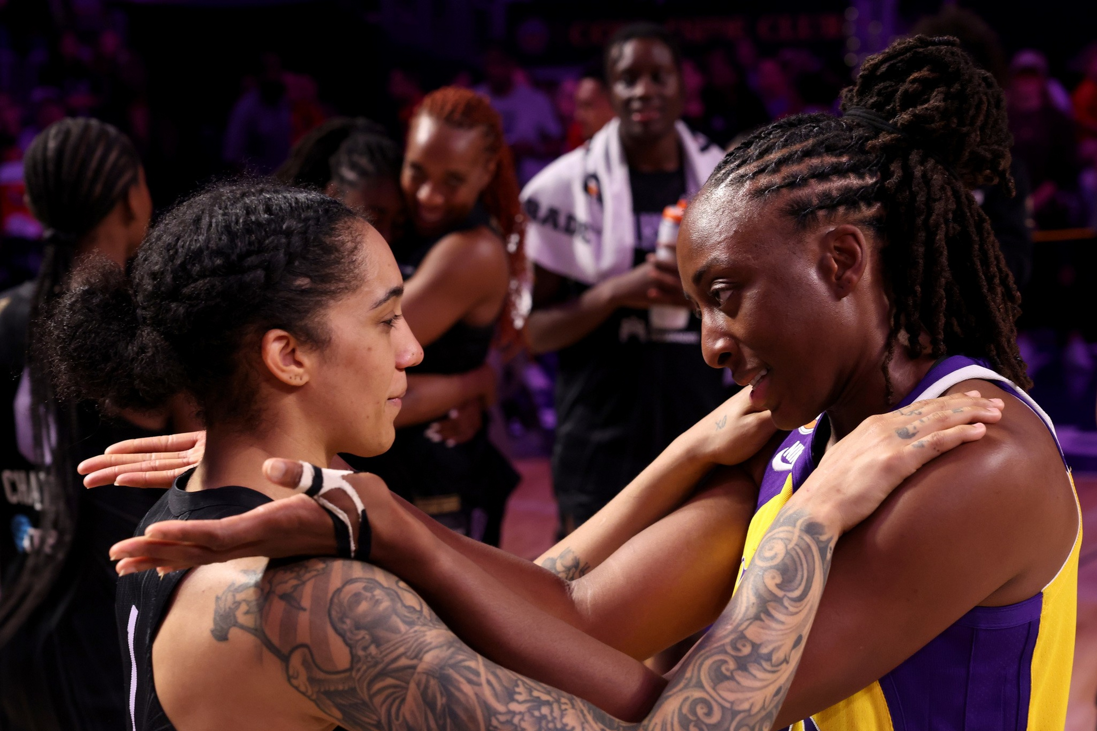 Two basketball players face each other closely, holding each other's shoulders with intense, focused expressions after a game.